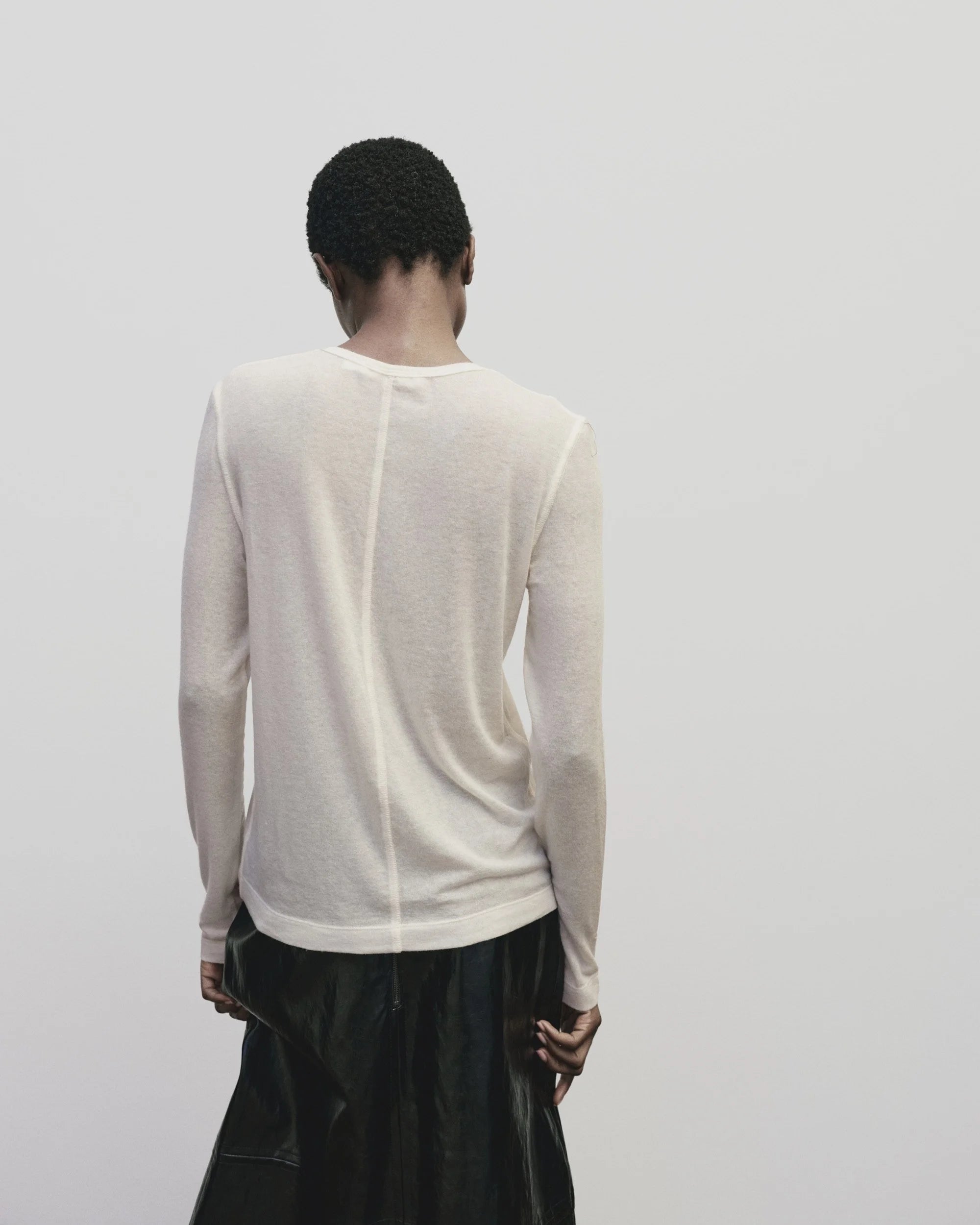 Back view of woman standing wearing a Mijeong Park Ivory Wool Tencel Crewneck Top at Alas Eius