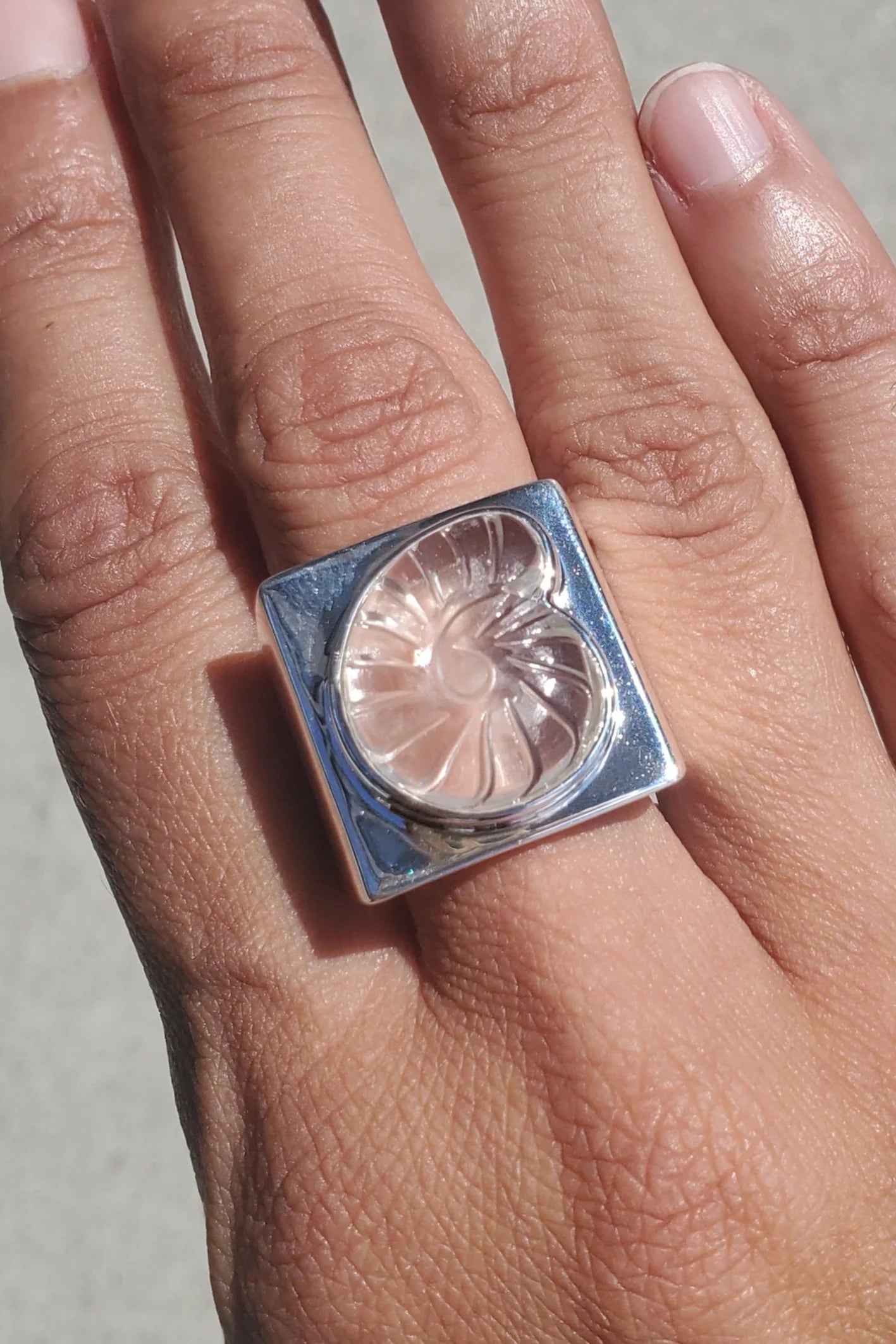 Contemporary design in a Nomia statement ring crafted in high polished solid sterling silver with a clear hand carved Nautilus Stone design at an Alas Eius store.