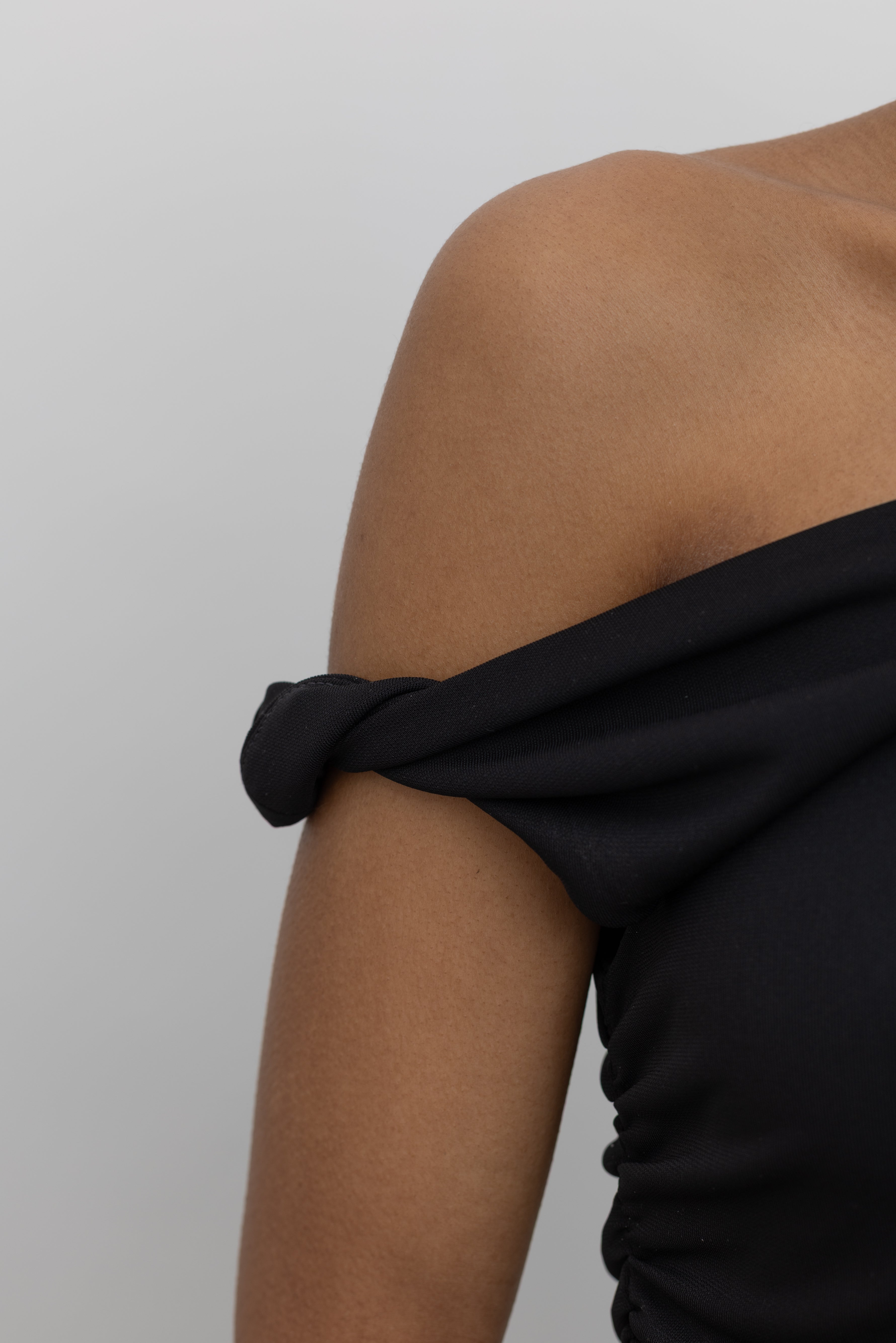Close-up detail of twisted off the shoulder straps on elevated Spring fashion Nomia black top at Alas Eius.