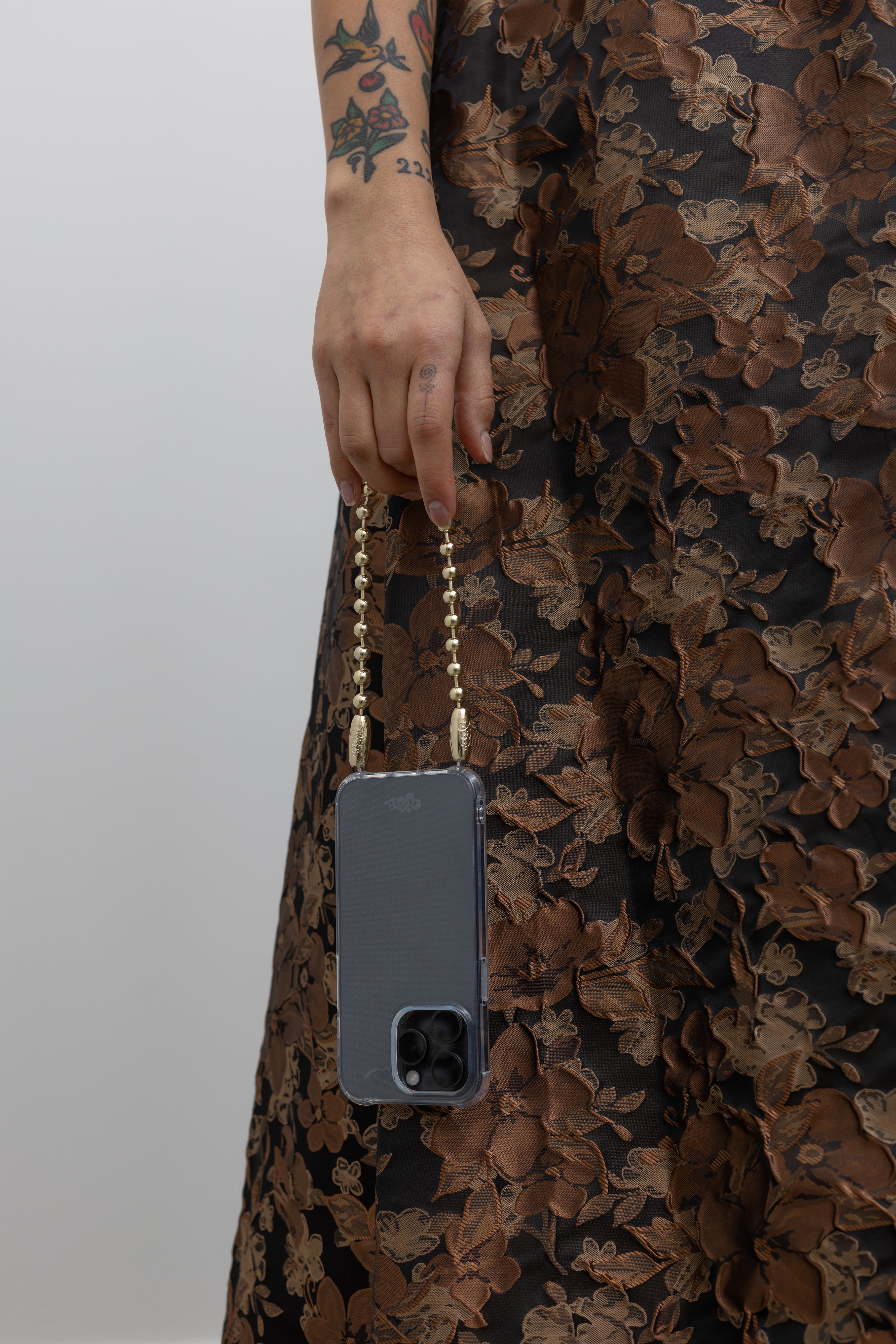 Woman holding the Ossa Ball Chain iPhone Wristlet Cord in High Polished Metal at Alas Eius