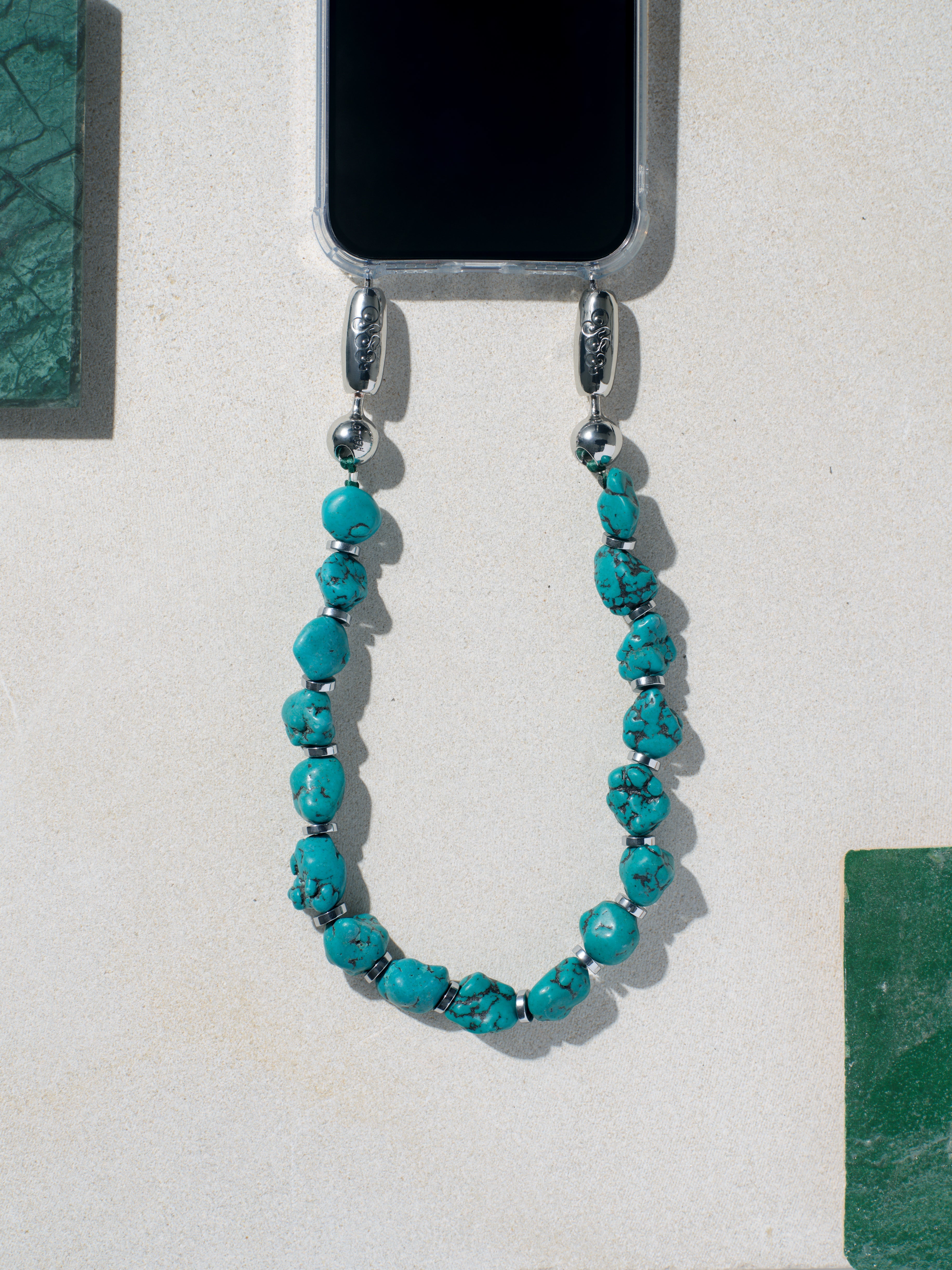 High polished gemstone chips strung together with silver hematite disks to create the Ossa Turquoise linked gemstone iPhone wristlet chain accessory at Alas Eius. 