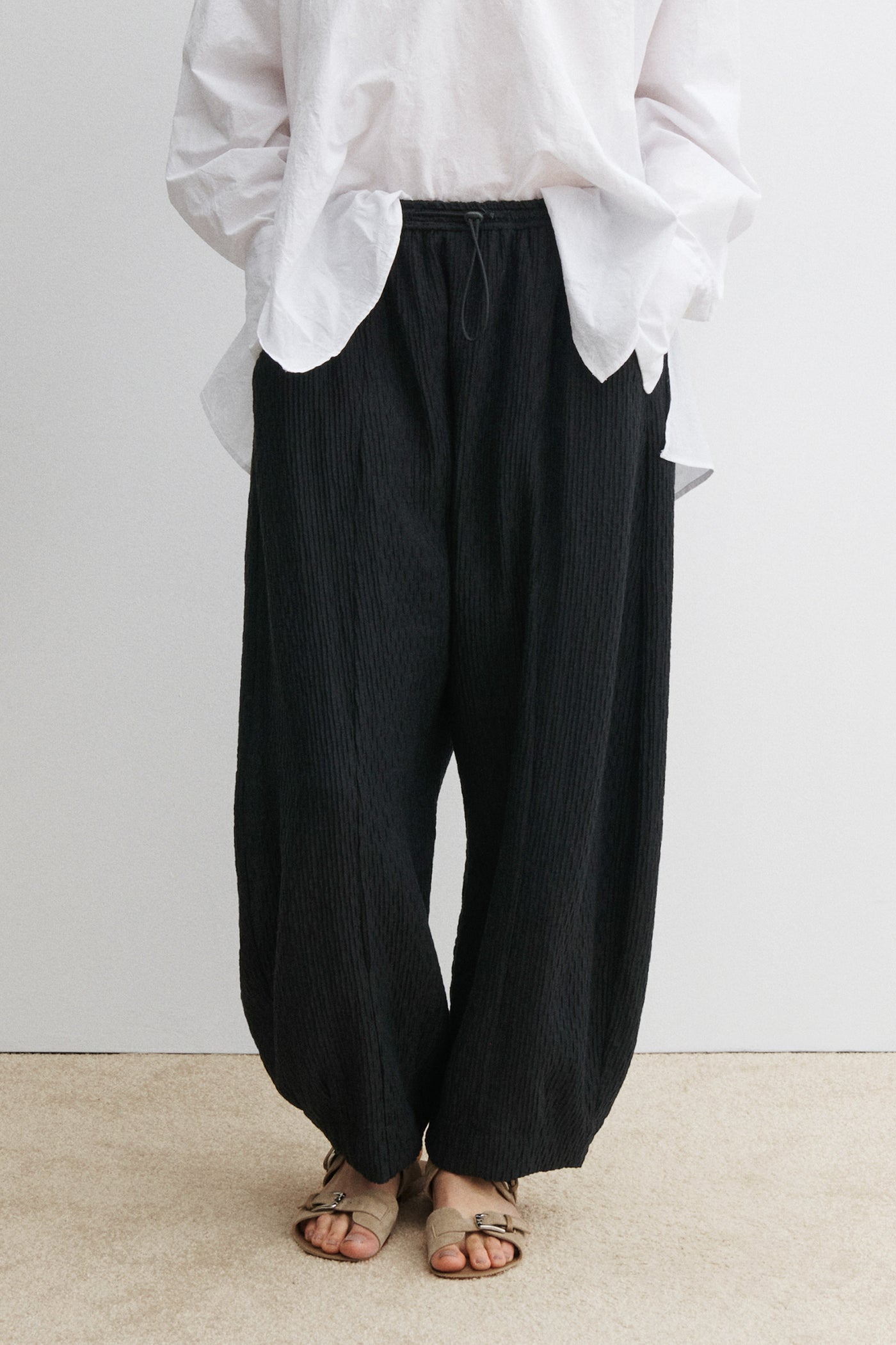 Front view of a woman wearing elevated casual and chic spring summer fashion in the Rachel Comey Black Ashbolt Pant featuring a relaxed wide-leg, elasticated drawstring waistband, two side seam pockets at an Alas Eius store. 