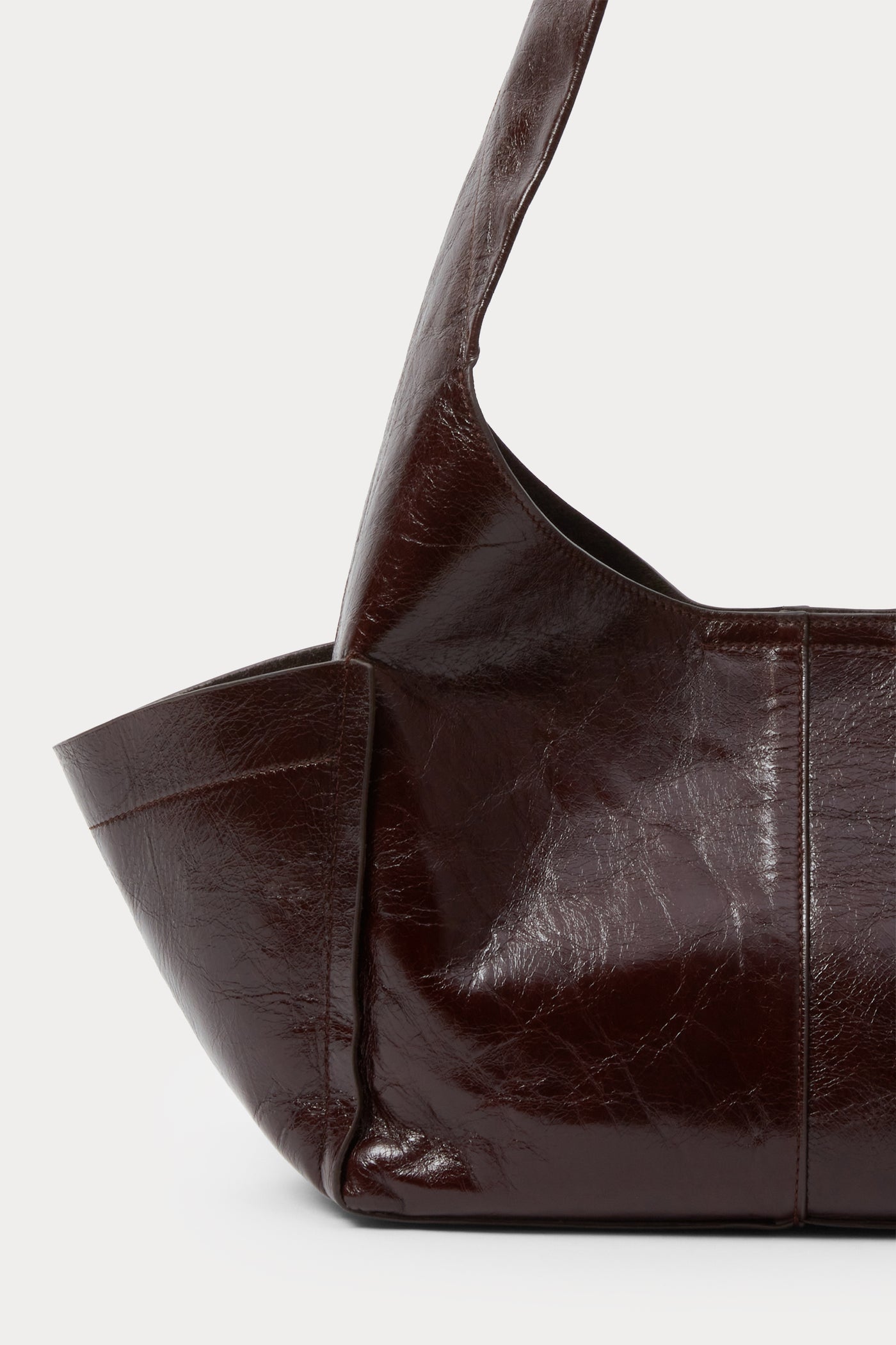 Close-up view of the outside pocket on the versatile Rachel Comey Chestnut Leather Tool Bag featuring a fixed shoulder strap, extended exterior pockets, and magnetic closure. Can be worn over the shoulder or across the body at an Alas Eius store. Made in Italy. 