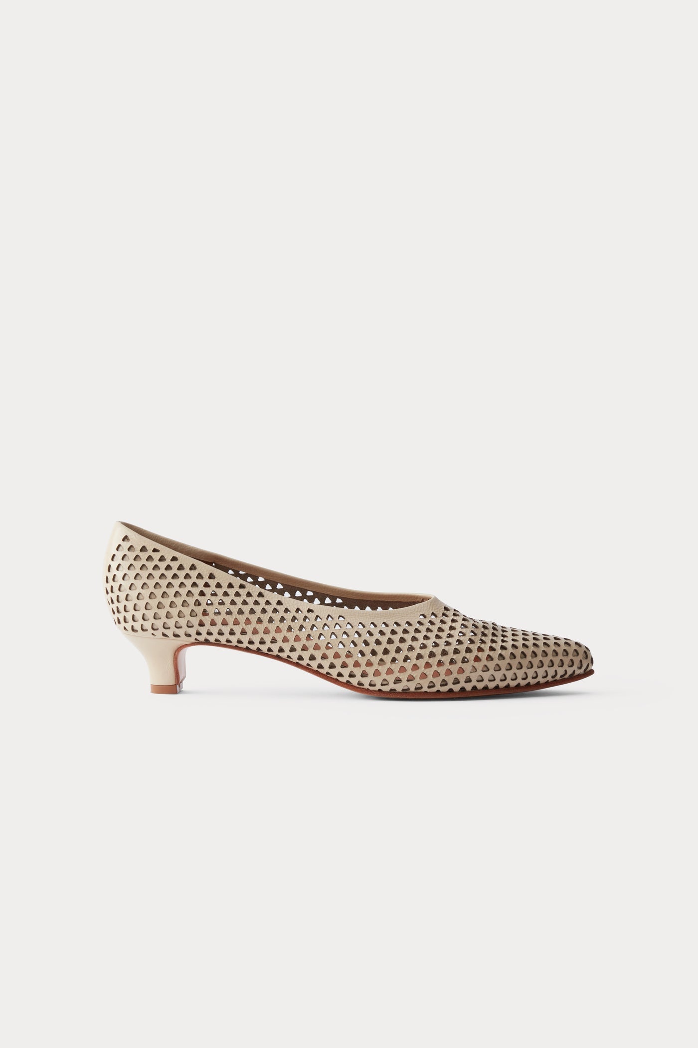 Side view of the chic and sophisticated Rachel Comey Champagne Clemmie Kitten Heel featuring a pointed-toe with a perforated triangular design on crinkle patent leather at an Alas Eius store.
