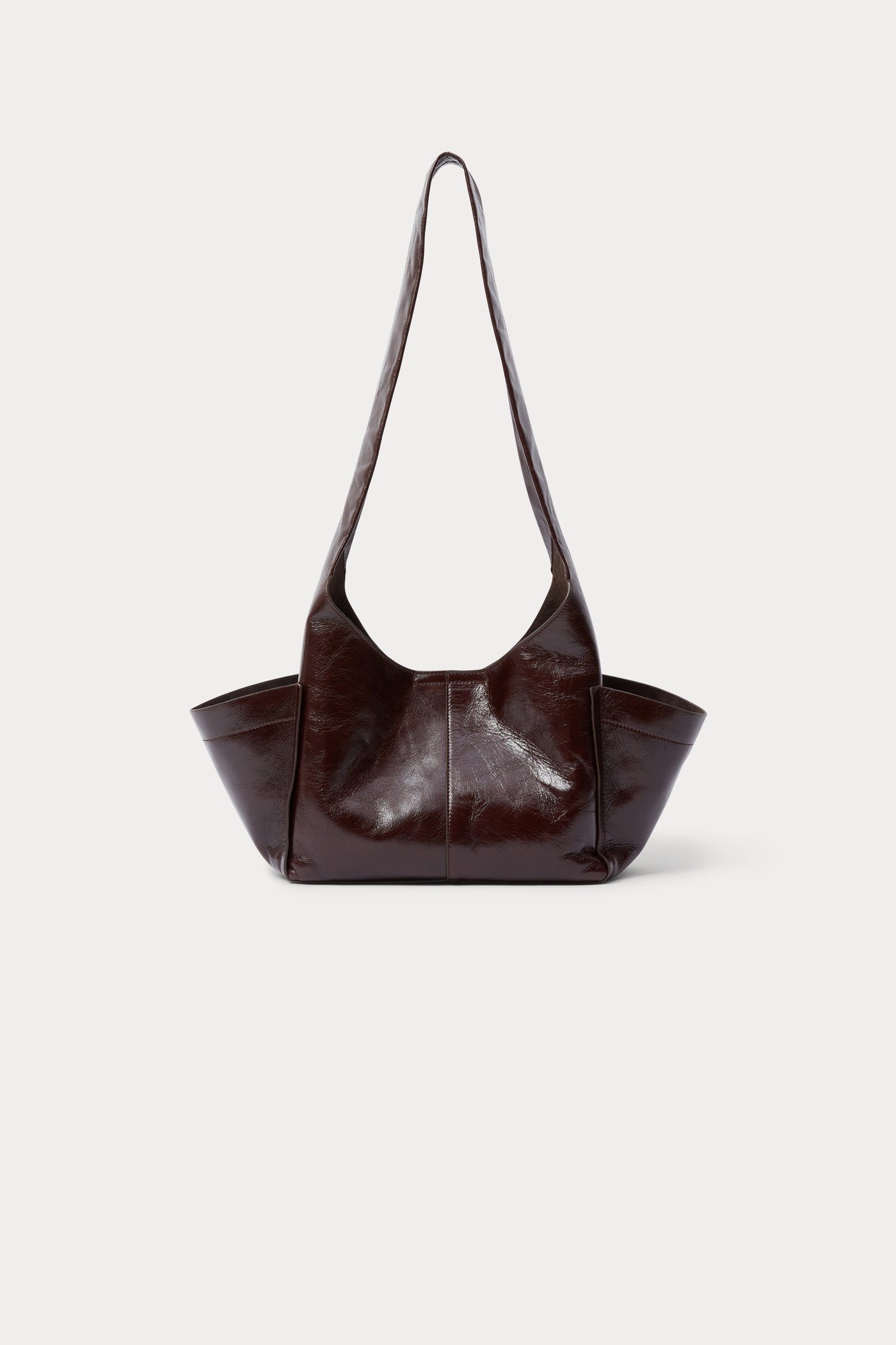 Product view of a modern and chic Rachel Comey Chestnut Leather Tool Bag featuring a fixed shoulder strap, extended exterior pockets, and magnetic closure. Can be worn over the shoulder or across the body at an Alas Eius store. Made in Italy. 