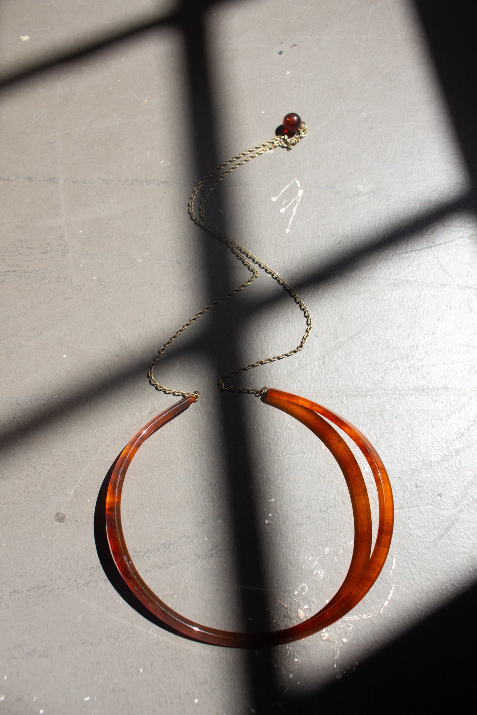 Rachel Comey Dark Tortoise Priori  Semi-Rigid Choker with Chain crafted from matte acrylic with an open back. Suspended from each end of the collar is a delicate brass chain that falls at the back, finished with a single bead accent at an Alas Eius store. 