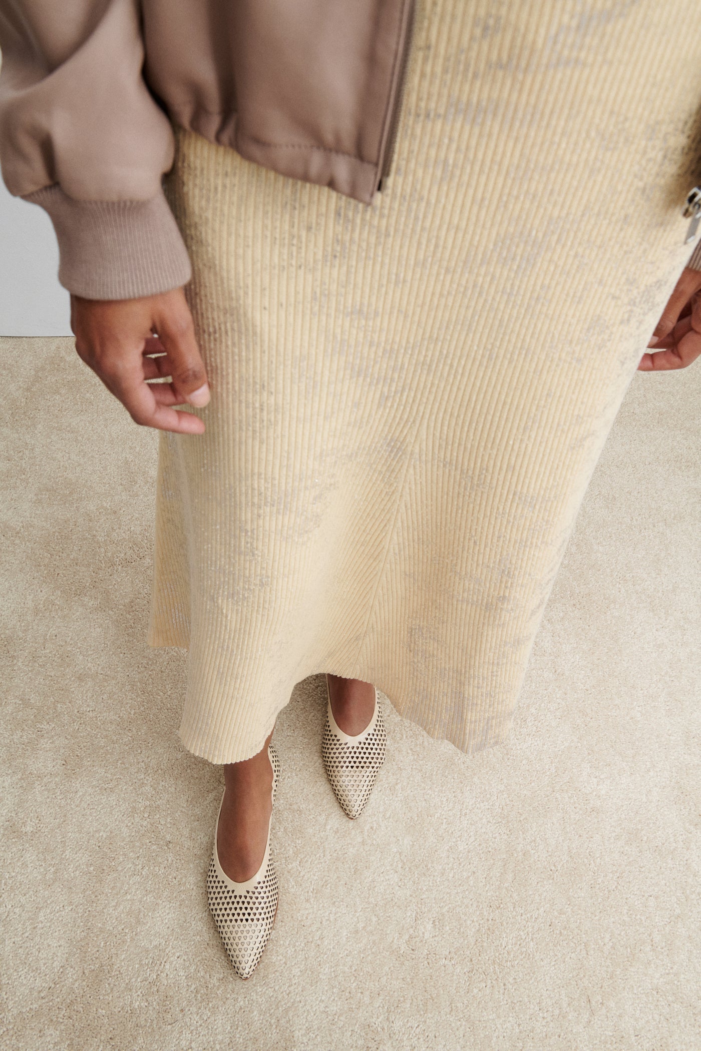 Aerial view of a woman wearing the chic and sophisticated Rachel Comey Champagne Clemmie Kitten Heel featuring a pointed-toe with a perforated triangular design on crinkle patent leather at an Alas Eius store.