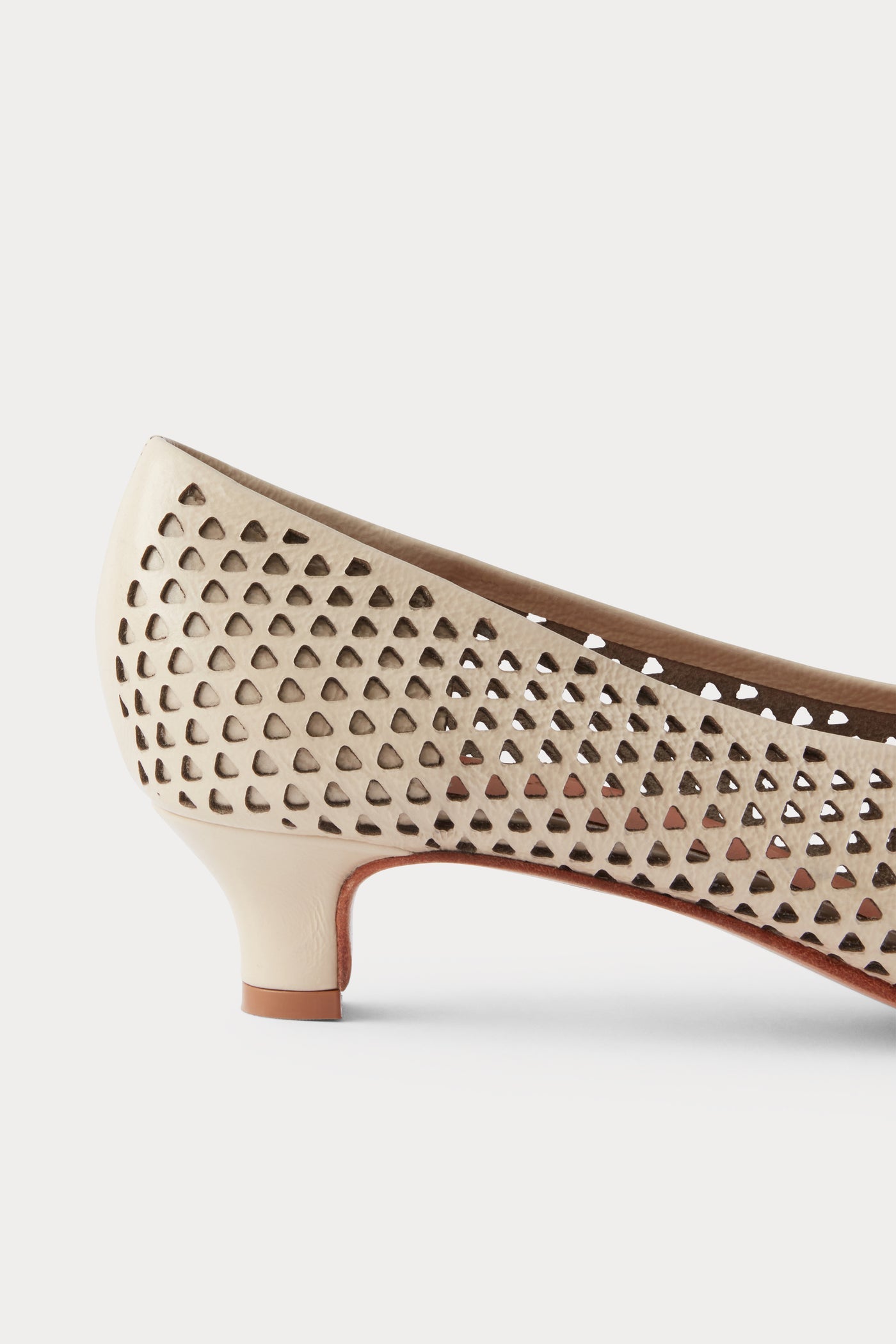 Side view of the chic and sophisticated Rachel Comey Champagne Clemmie Kitten Heel featuring a pointed-toe with a perforated triangular design on crinkle patent leather at an Alas Eius store.