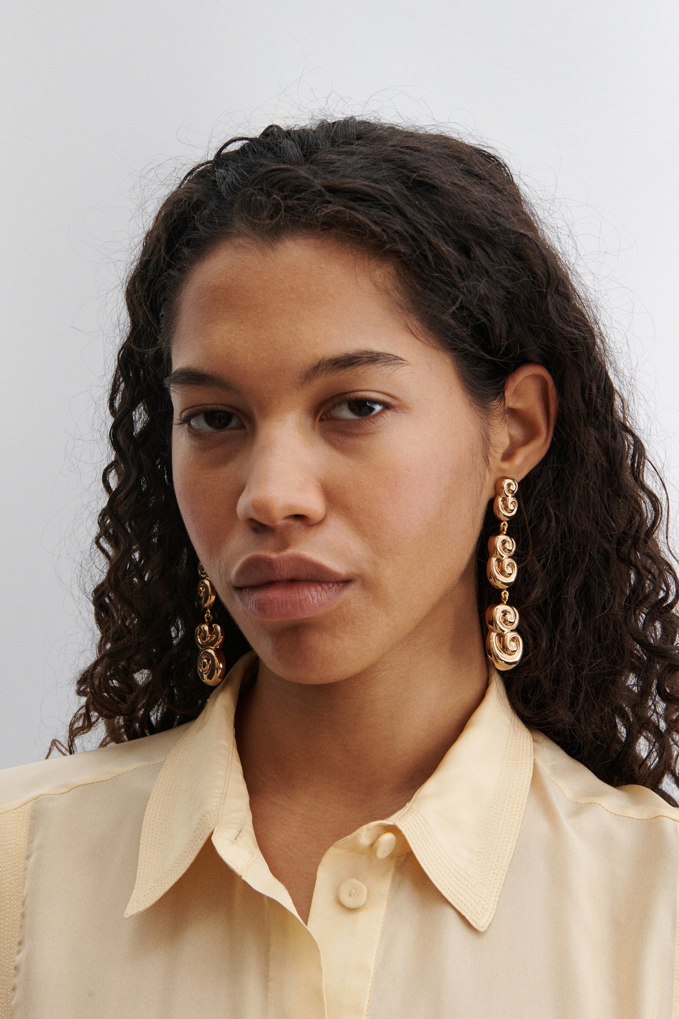 Woman wearing elegant and chic Rachel Comey Old Gold Croissant Swirl Drop Stud Earrings at Alas Eius.