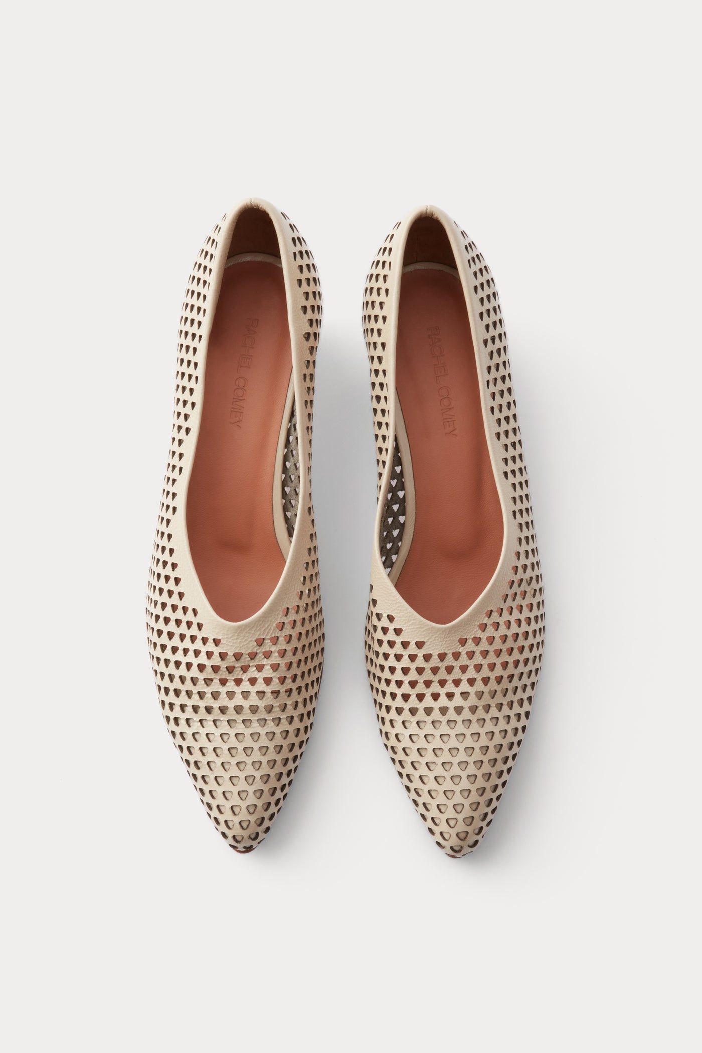 Aerial view of the chic and sophisticated Rachel Comey Champagne Clemmie Kitten Heel featuring a pointed-toe with a perforated triangular design on crinkle patent leather at an Alas Eius store.
