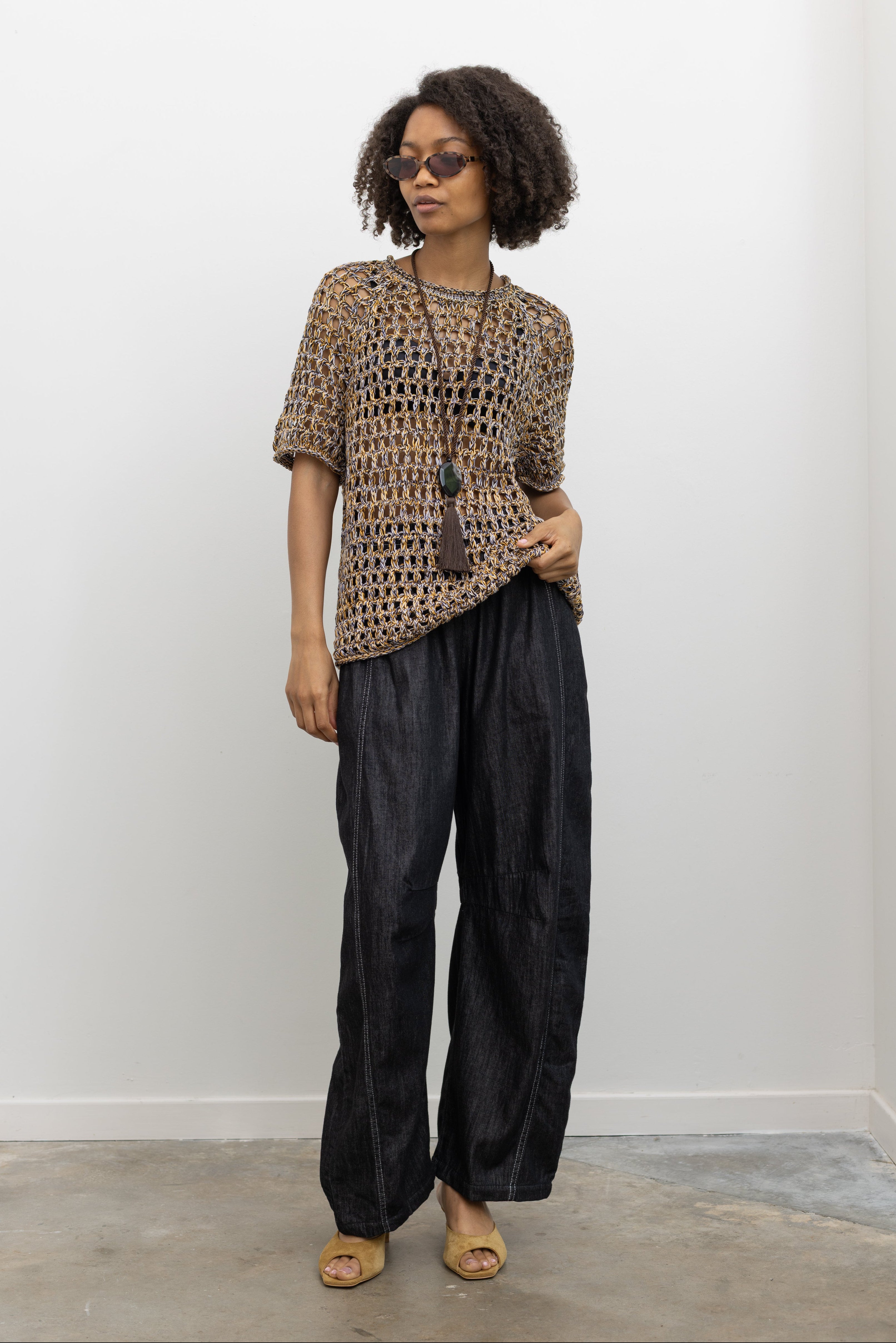 Model wearing chic summer fashion in a Rachel Comey colorful cotton knit top with an open-weave design, crew neckline, and effortless relaxed shape paired with flattering Alas Eius label dark wash contrast stitch barrel pull on pant at Alas Eius.