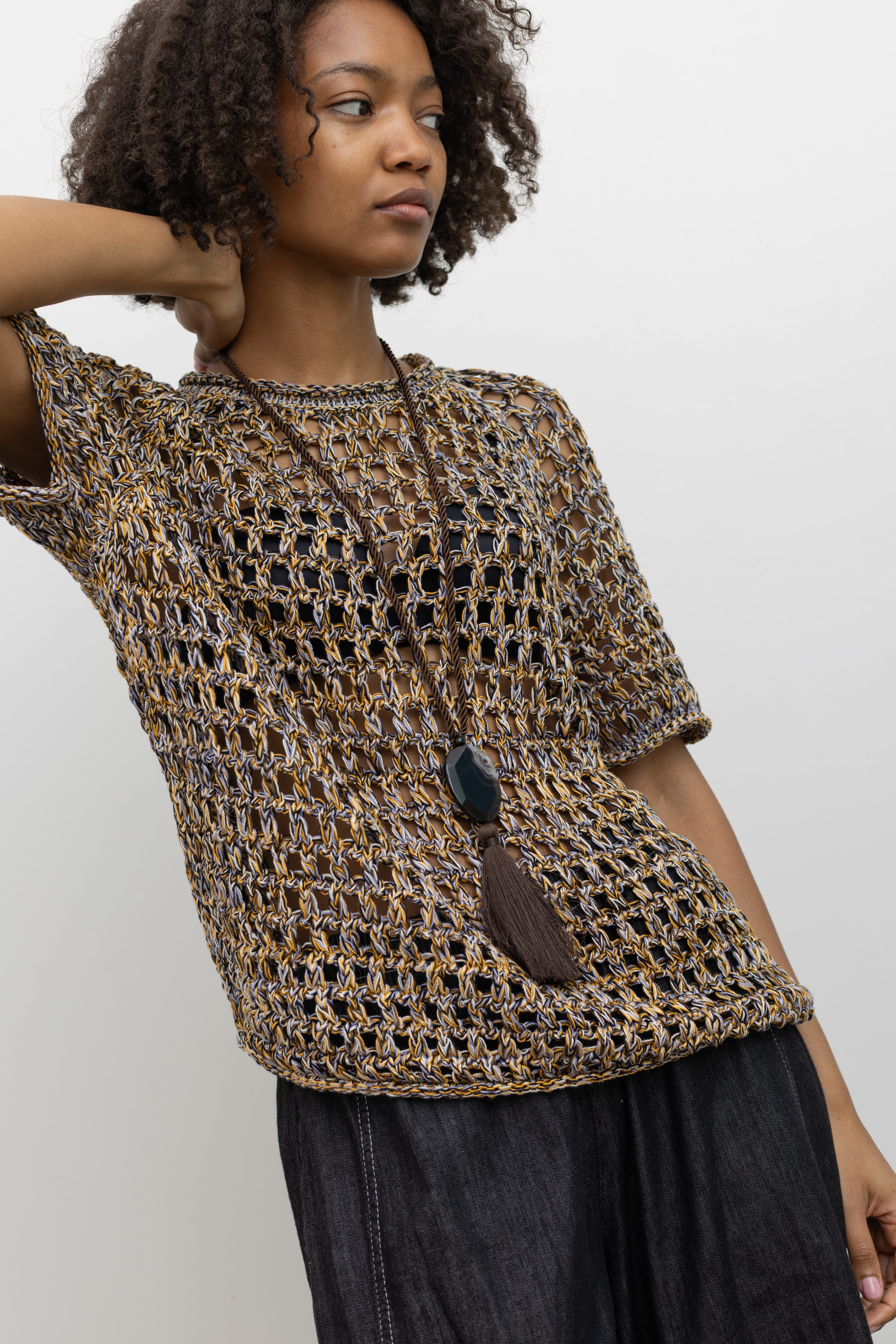 Model wearing Rachel Comey relaxed-fit open-knit pullover with colorful woven texture, rolled edges, and short sleeves for an airy summer look at Alas Eius. 