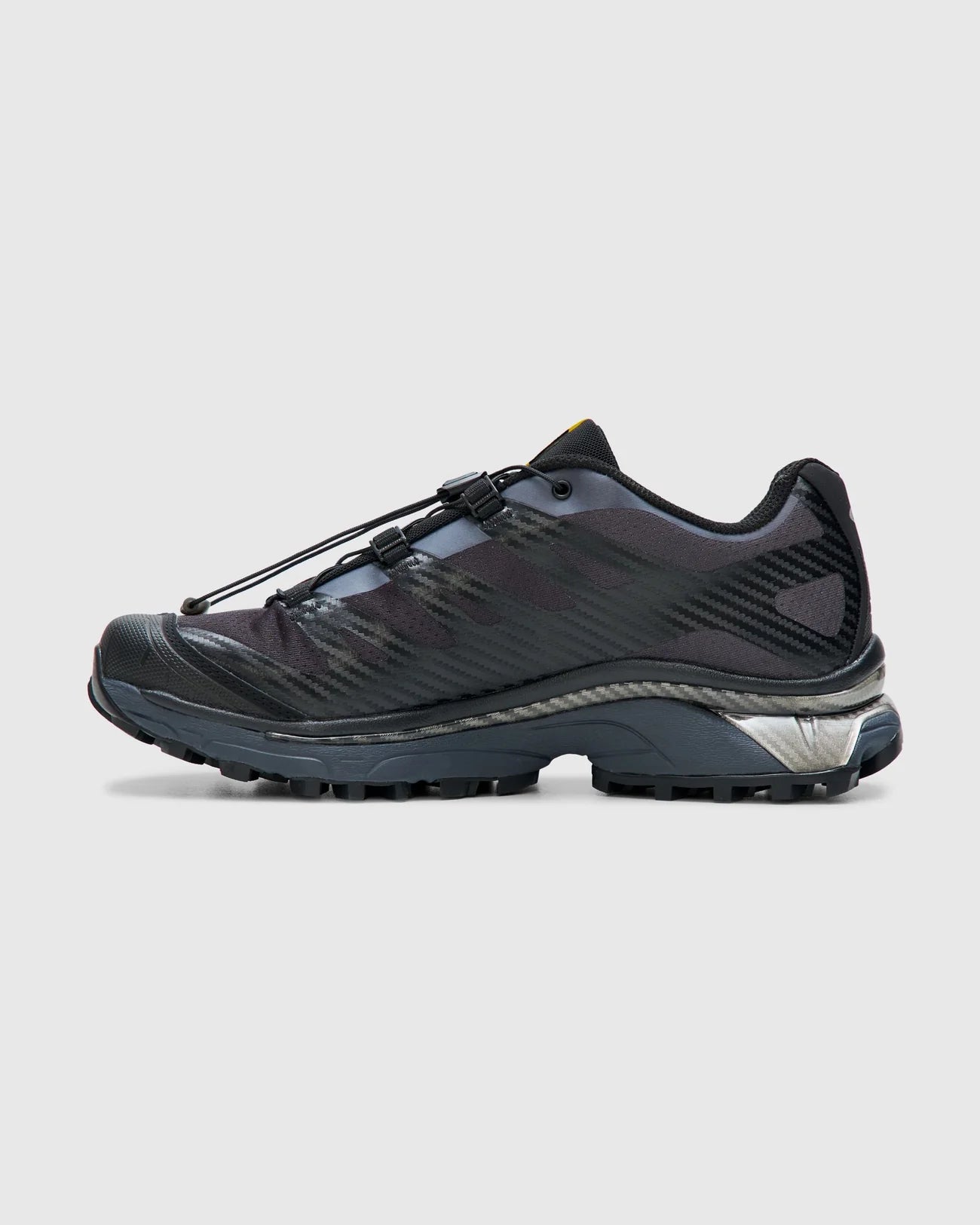 Side view of the Salomon XT-4 OG Black and Ebony Sneakers featuring quicklace bungy laces and in a sleek and modern black with primary color detail on the tongue suited to contemporary urban wear at an Alas Eius store. 