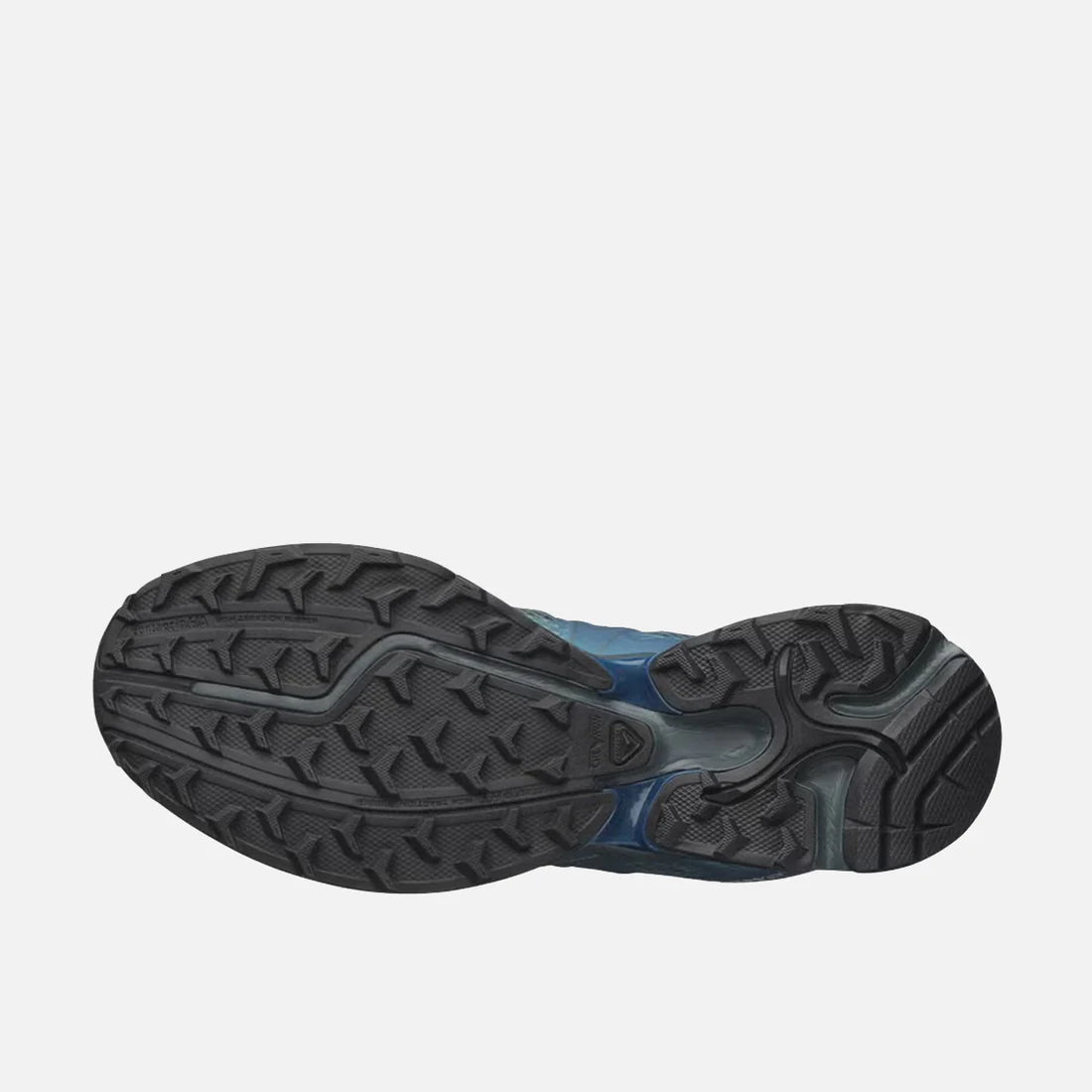 Outsole view of a pair of modern and elevated Salomon XT-Whisper Void Sneakers in a iridescent Dark Slate and Gibraltar Sea colorway featuring quickLACE a minimalistic and strong lace for one-pull tightening and easy-on, easy-off on a white shelf at Alas Eius.