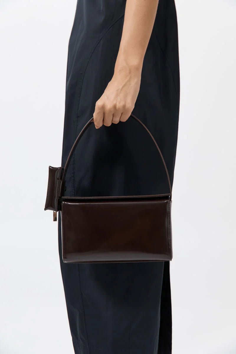 Woman holding a sleek and sophisticated St. Agni Coffee Brown Leather Petit Pouch Bag at Alas Eius 