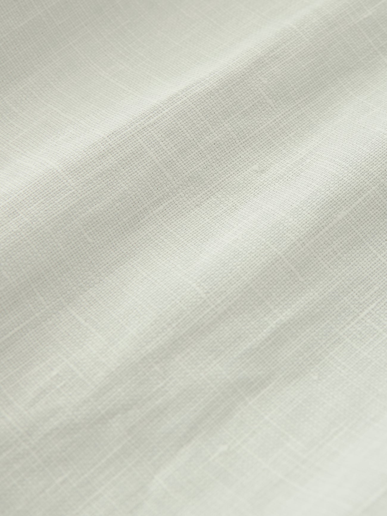 Close-up view of the coated linen fabric on the Studio Nicholson Bone Minos Pant at Alas Eius.