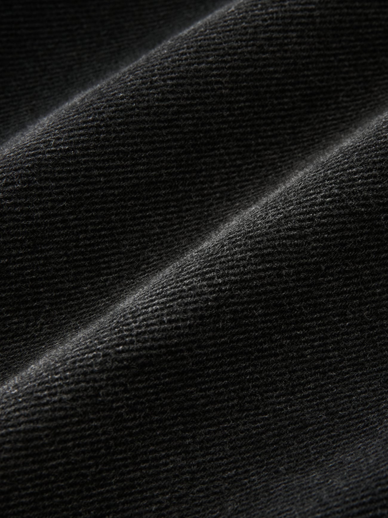 Close-up view of the regenerative cotton used to make the Studio Nicholson Washed Black Chalco Wide Crop Denim Pants at Alas Eius. Made in the UK.