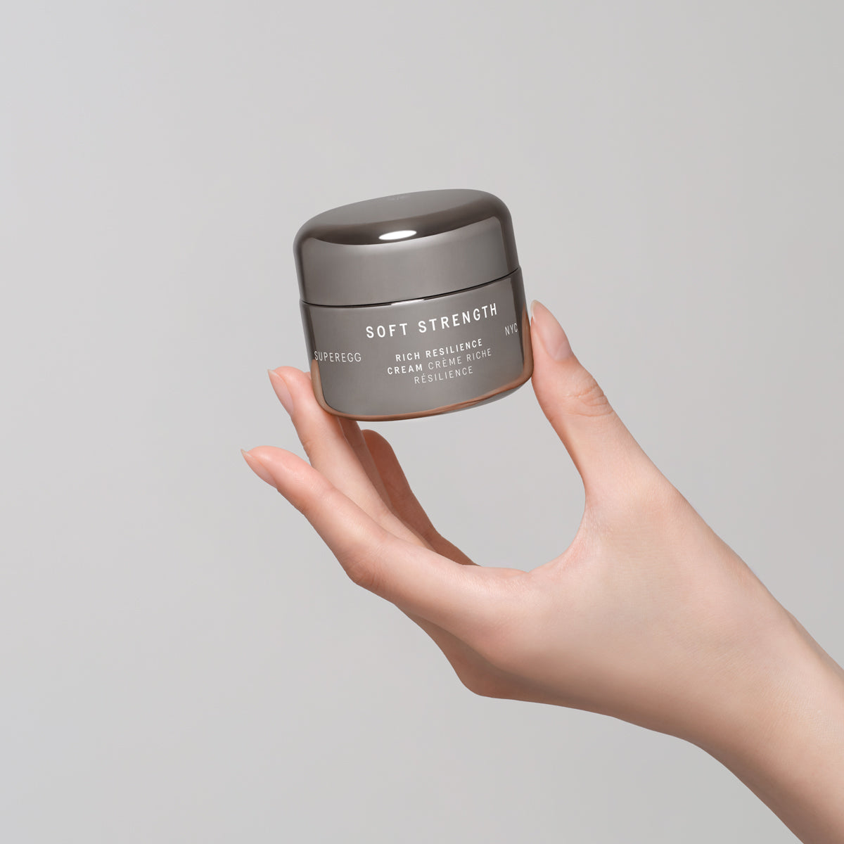 Woman holding a container of the non-toxic, anti-aging Superegg Soft Strength Rich Face Cream designed to firm, smooth, and build skin resilience. The cream is made in Korea and Paraben-free; phthalate-free; sulfate-free; silicone-free; fragrance-free; oil-free at Alas Eius.