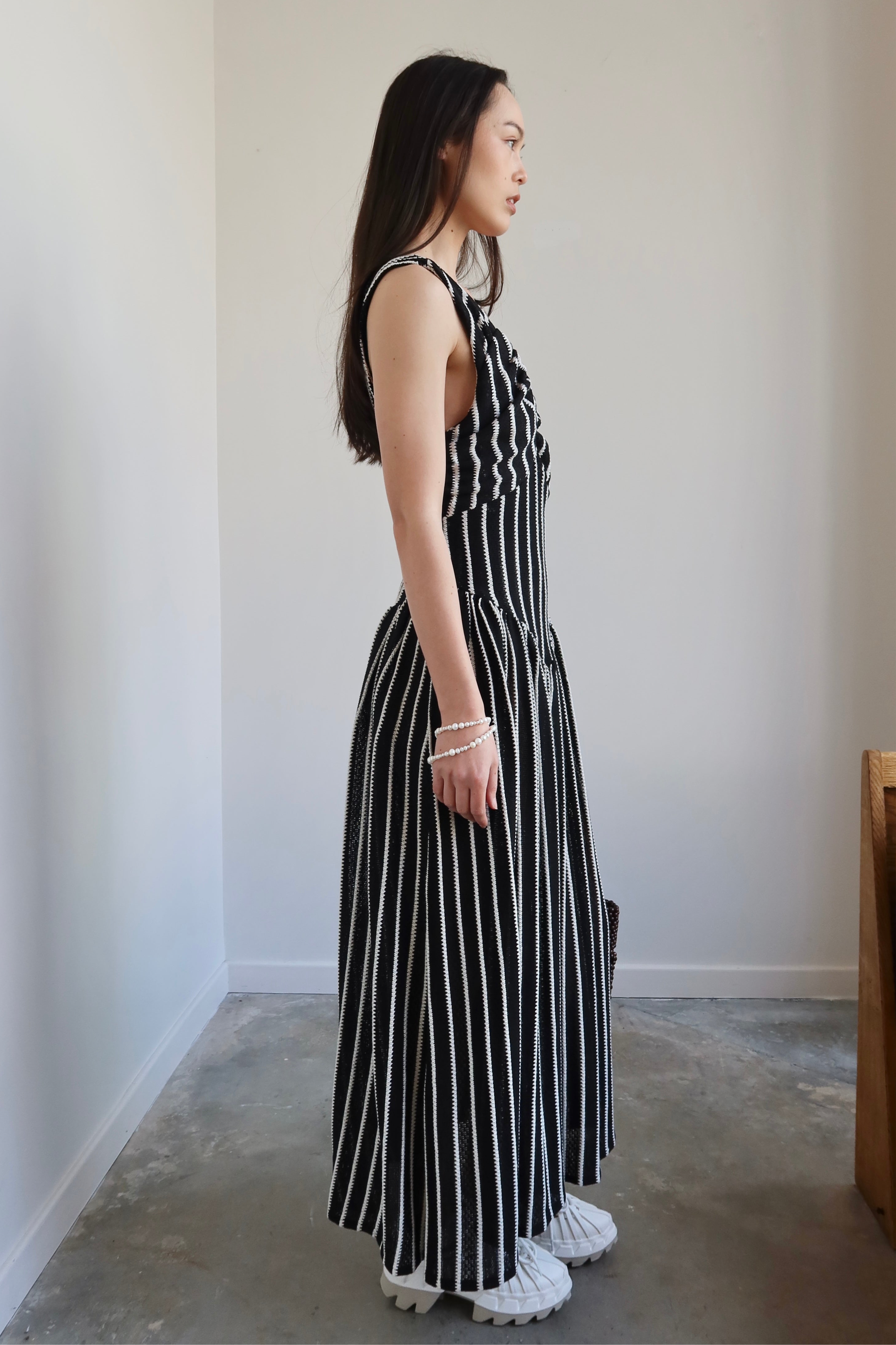 Full length side view of a woman wearing Tach Ikia Black Striped Knitted Maxi Dress at Alas Eius