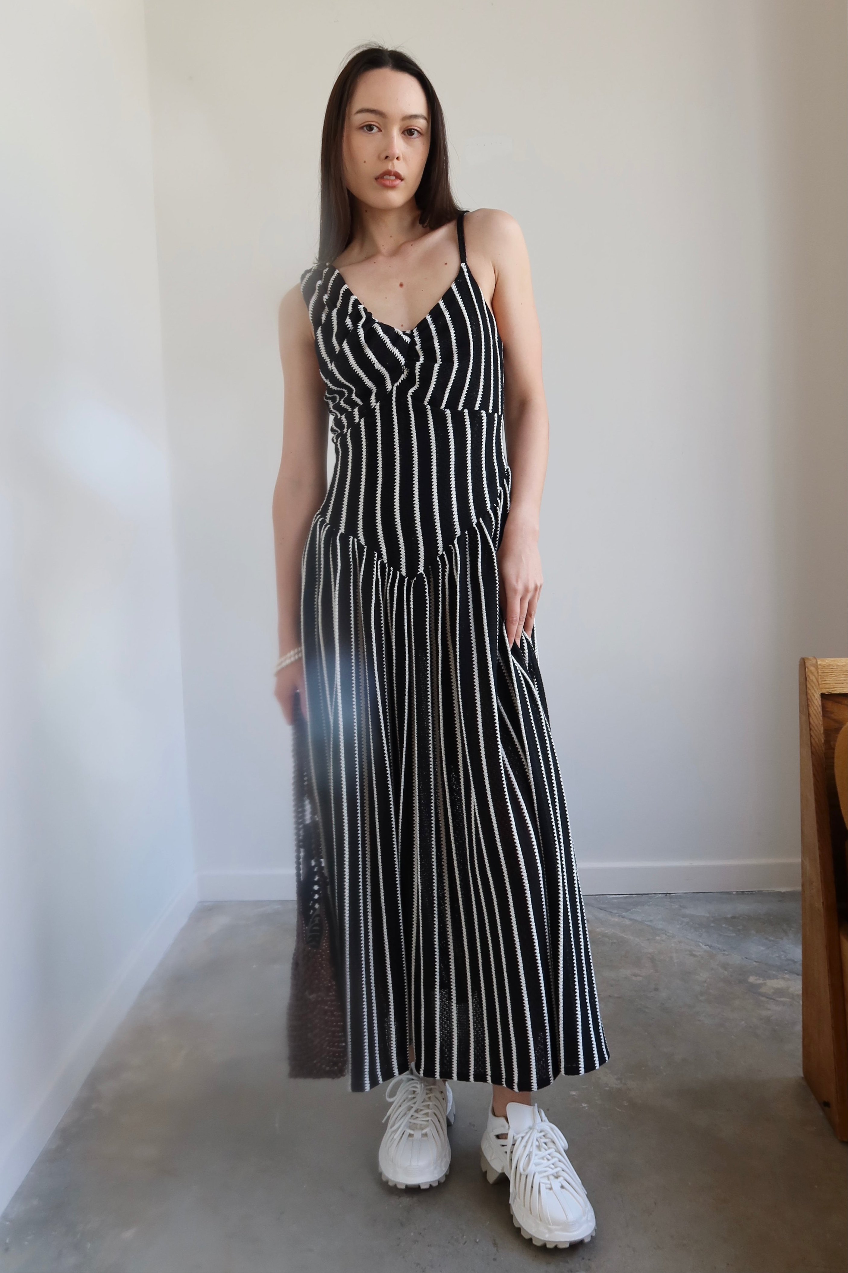 Full length front view of a woman wearing Tach Ikia Black Striped Knitted Maxi Dress at Alas Eius