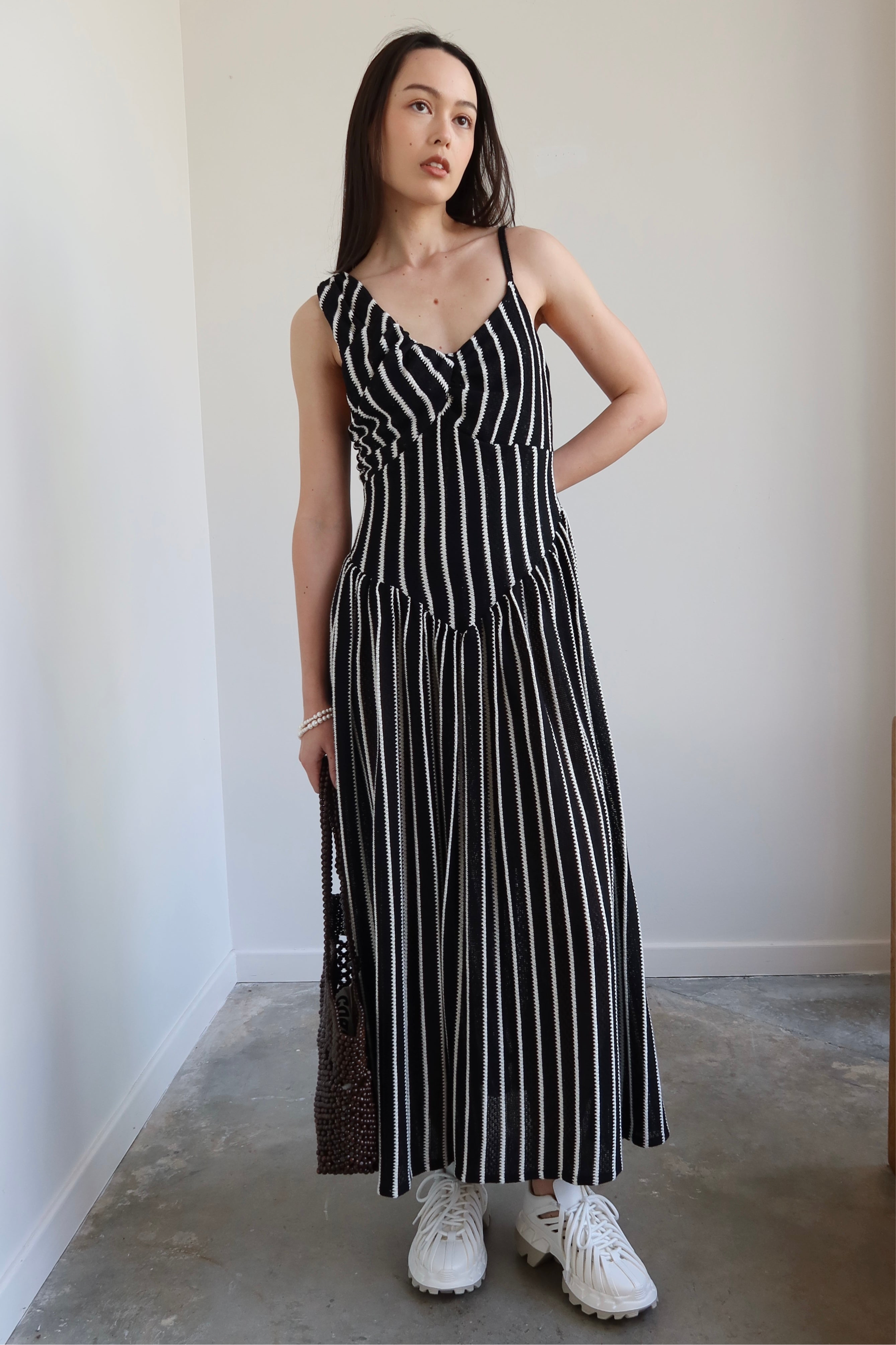 Full length front view of a woman wearing Tach Ikia Black Striped Knitted Maxi Dress at Alas Eius