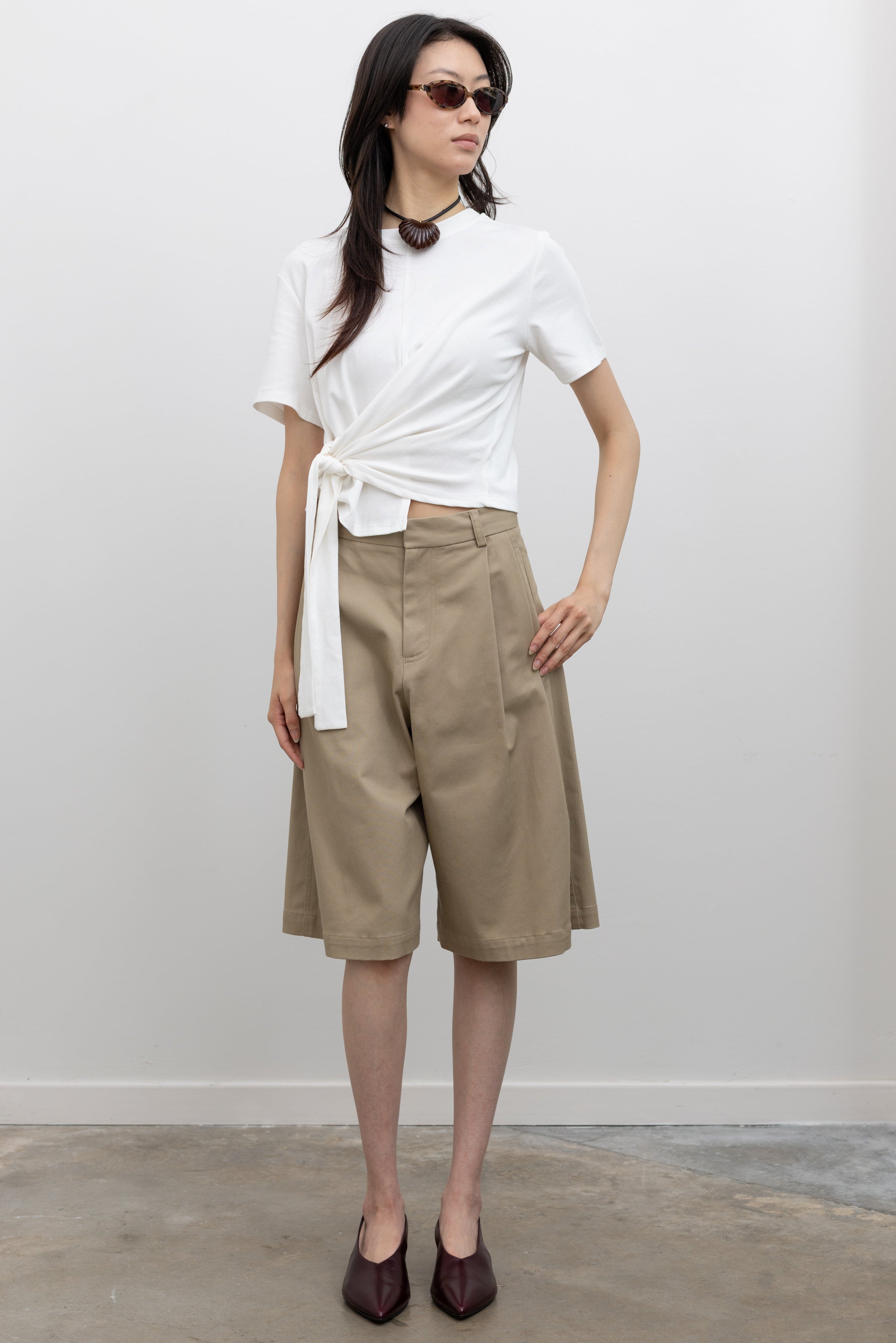 Tela women’s sand cotton gabardine Bermuda shorts with tailored fit, belt loops, and white drawstring detail, a versatile luxury casual wardrobe staple at Alas Eius
