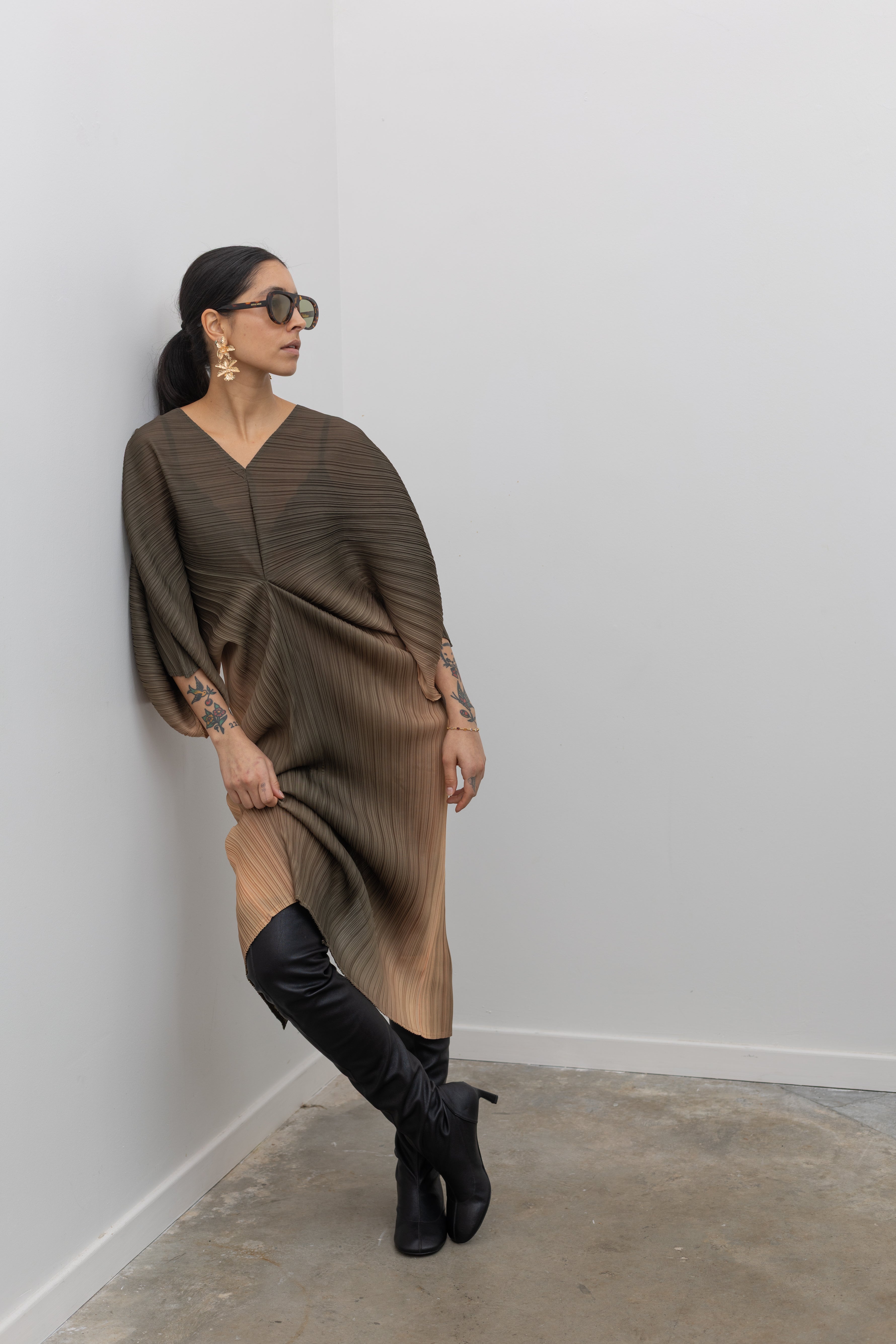 Woman leaning against a wall wearing Tela Macob Black Leather above-the-knee Heeled Boots paired with a dress at Alas Eius