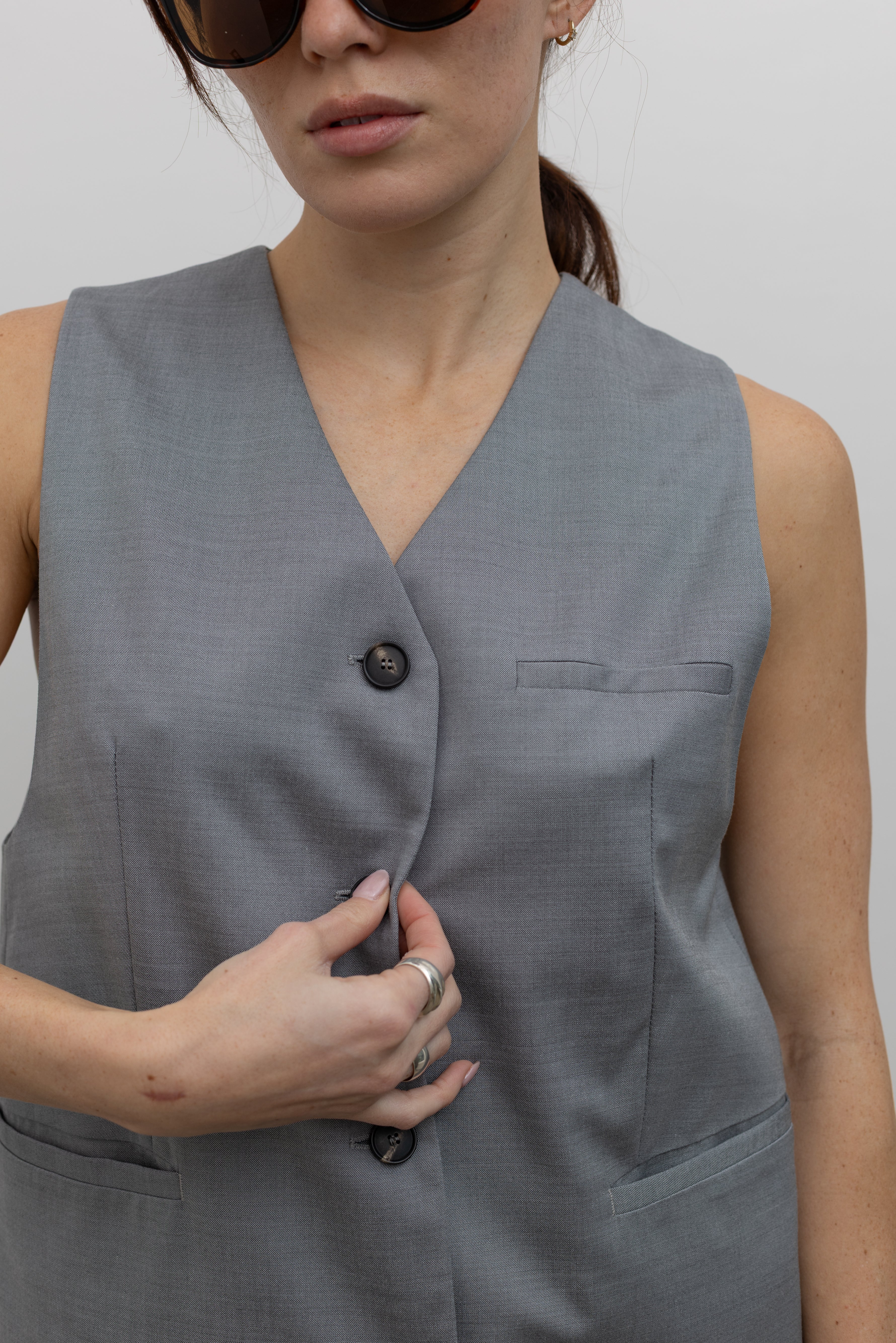 Close-up front view of a woman wearing Spring fashion in a sophisticated and refined Tela Gabriel Grey Cool Wool Button Down Vest at Alas Eius.