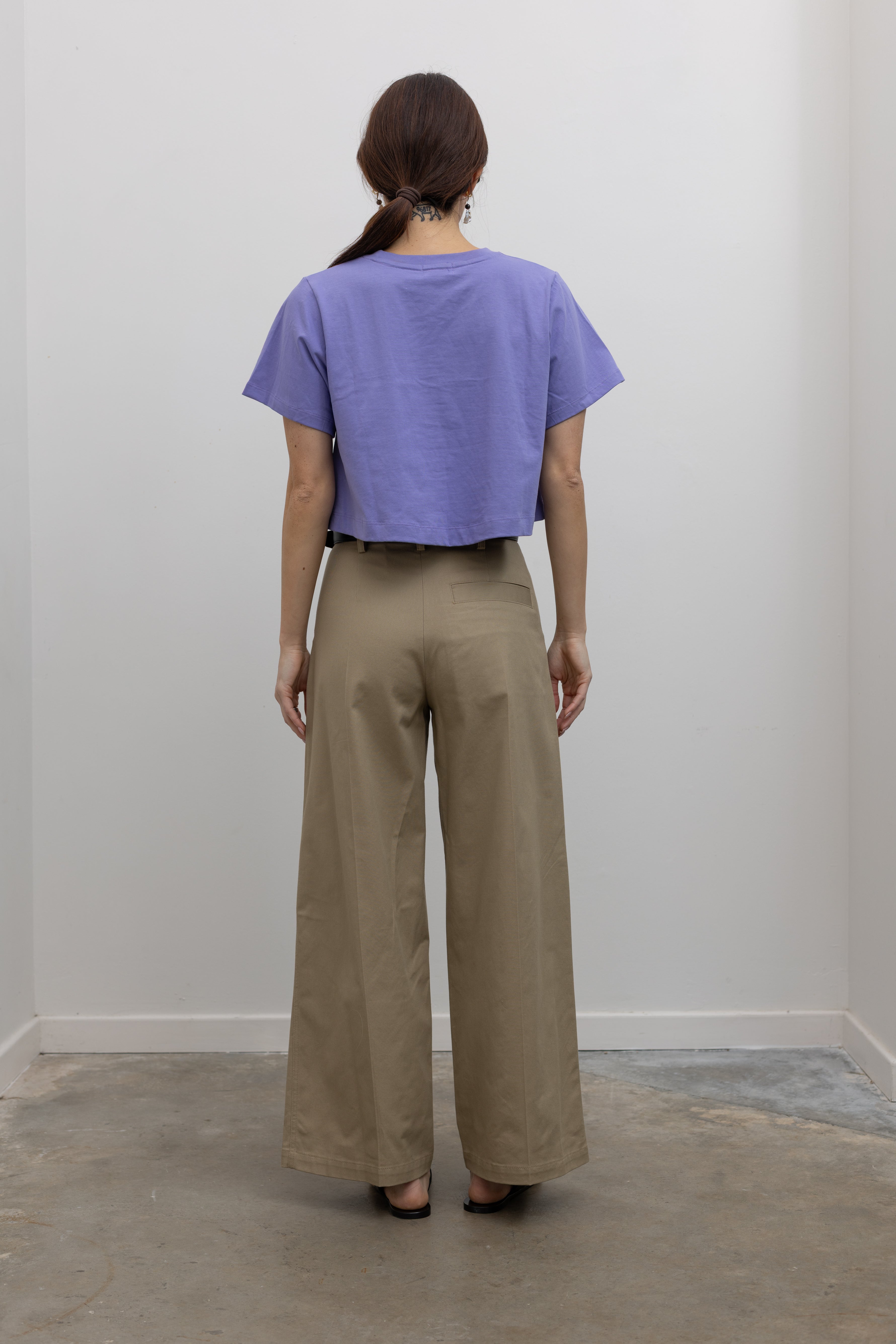 Back view of Woman standing wearing Spring fashion in a pair of Tela Rubicon Sand Cotton Gabardine Trousers and cropped blue tee at Alas Eius