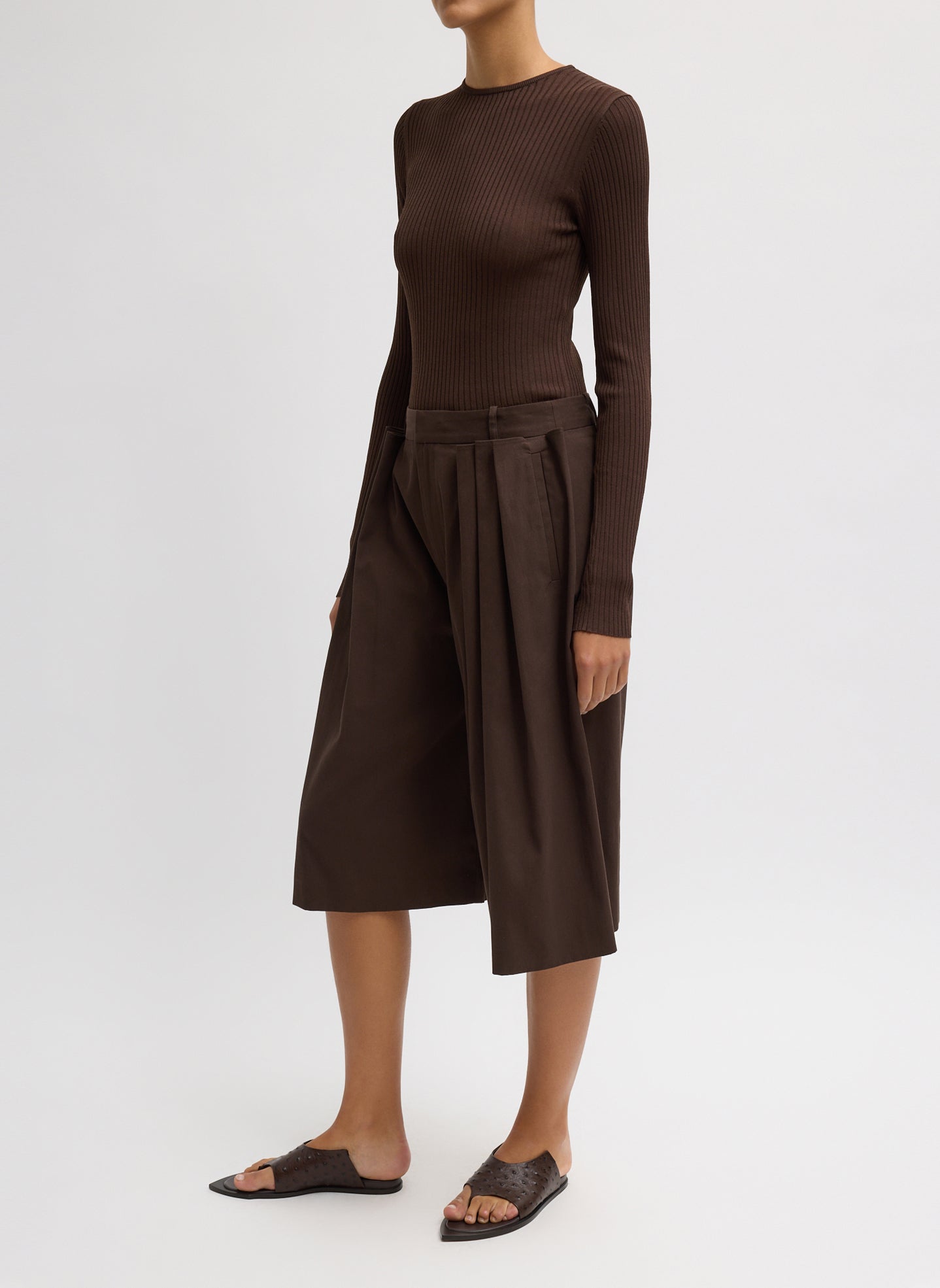 Side view of woman wearing Spring fashion in a brown ribbed sweater and Tibi Brown Luxe Spring Twill Tucked Pleated Wide Leg Short at Alas Eius