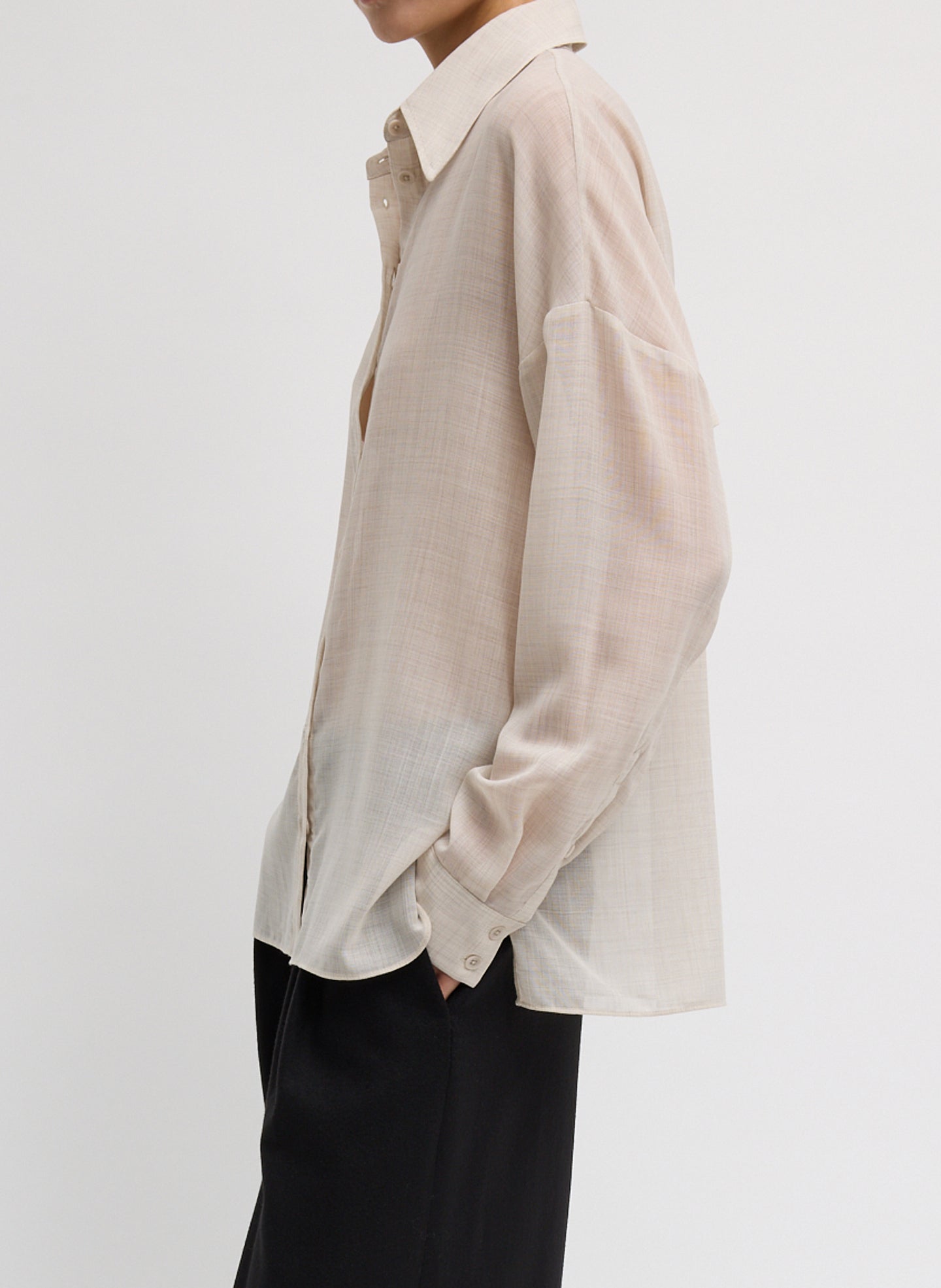 Side view of woman wearing Spring fashion in black trousers and a Tibi Oatmeal Sheer Wool Gauze Oversized Shirt at Alas Eius