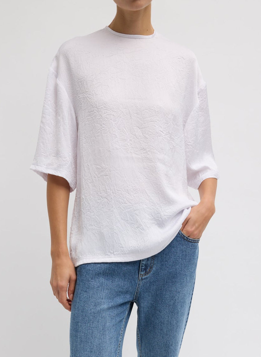 Woman wearing Spring fashion in light wash jeans and a Tibi White Crinkle Shirting Easy T-Shirt at Alas Eius