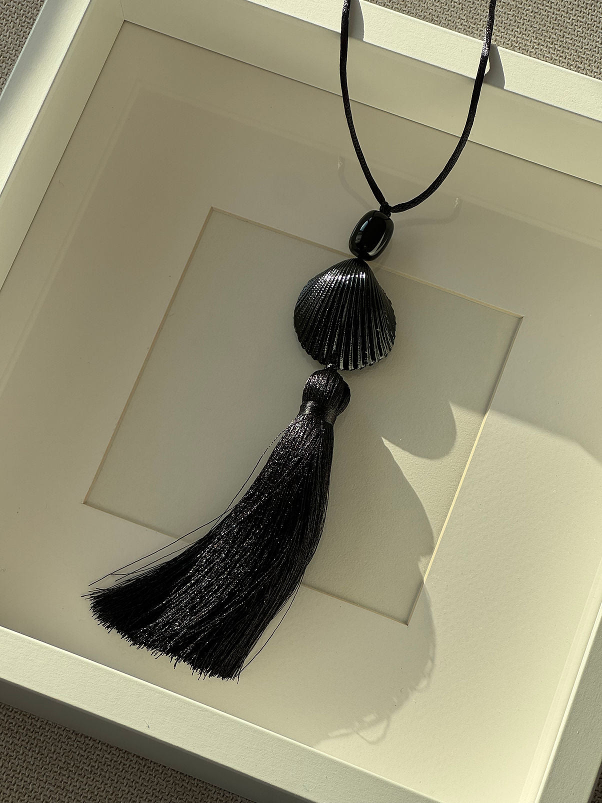 Black seashell silk tassel pendant necklace on an adjustable silk cord at Alas Eius. Made in Europe. 