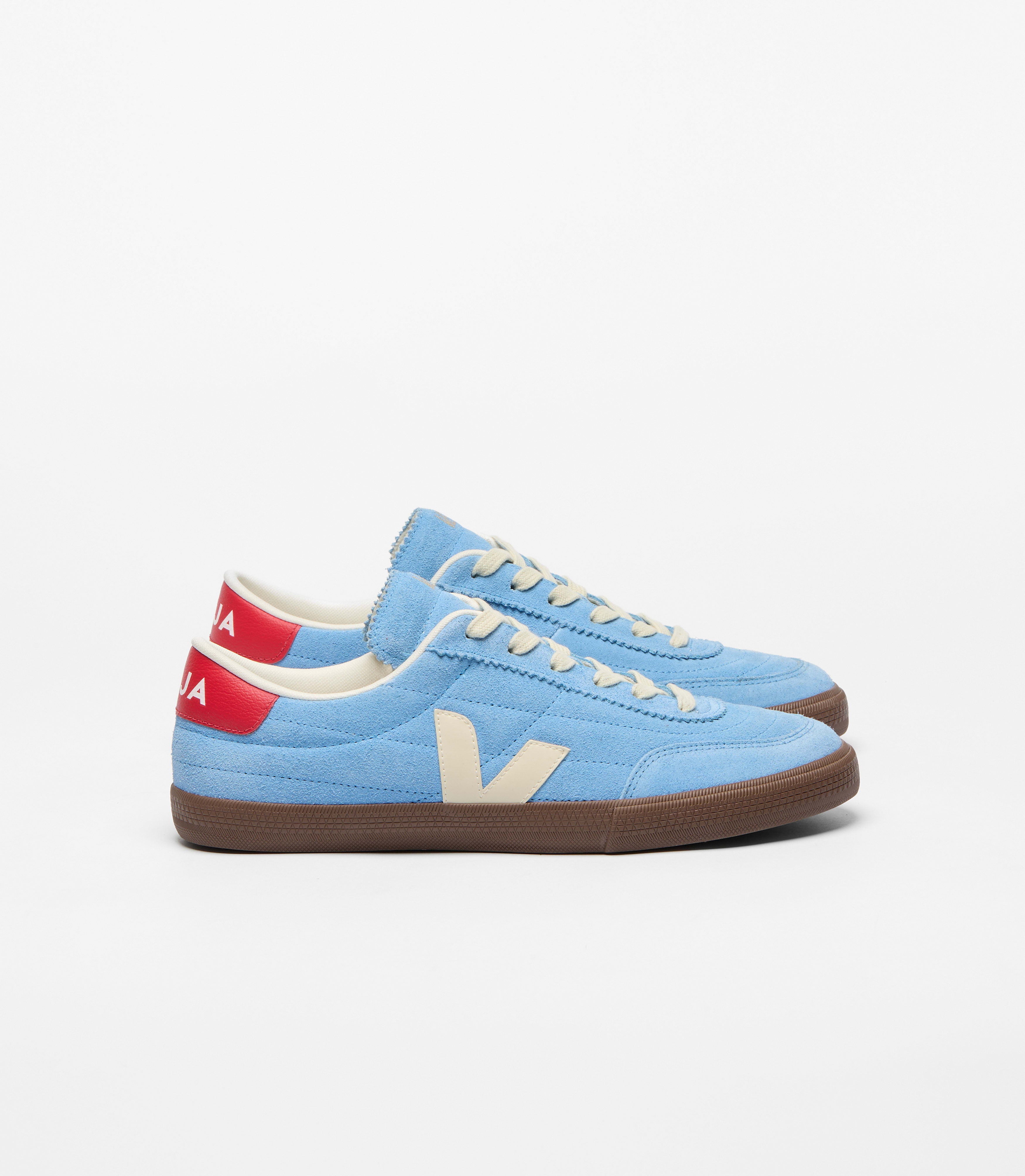 Veja sneakers in a sky blue suede upper paired with contrasting cream details and a rich brown sole. Finished with a bold red heel tab and signature side logo, the design blends sport and urban culture with modern everyday style at an Alas Eius store. 