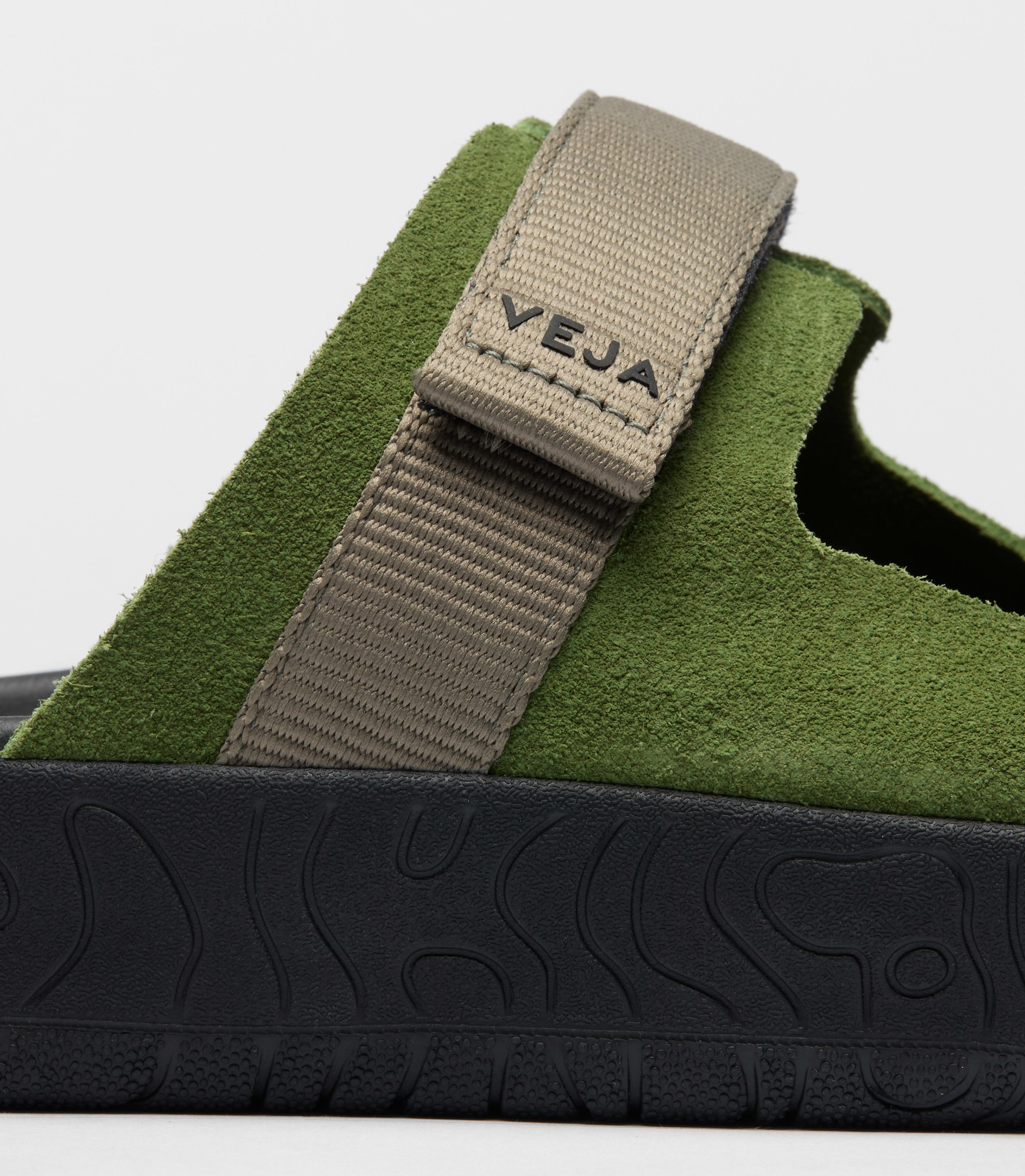 Close up view of the Veja Arpoador slide sandal featuring a vibrant green suede upper with gray adjustable strap set on a soft black footbed and lightweight platform sole at Alas Eius