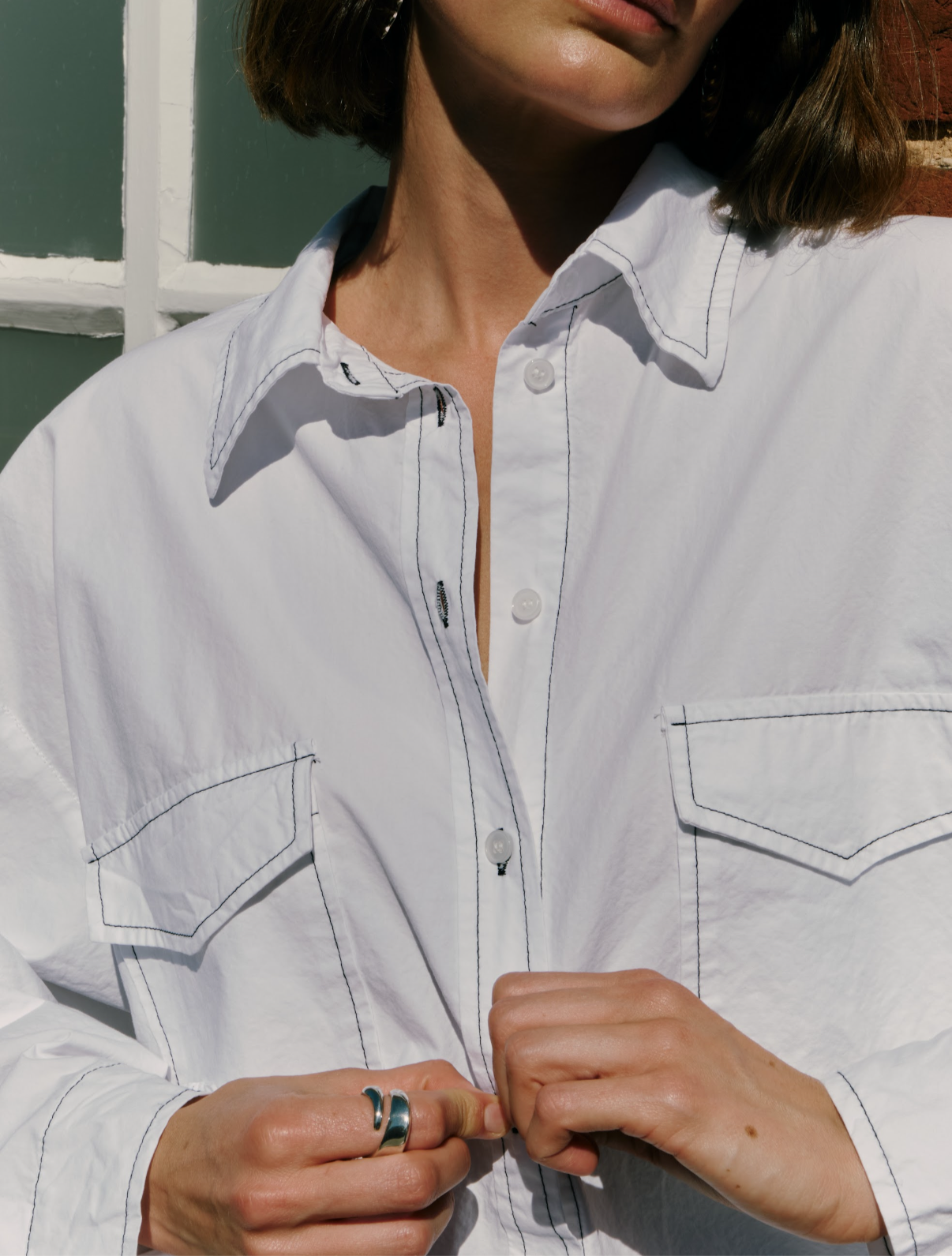 Close-up of a white shirt with a collar and buttons, worn by a person.
