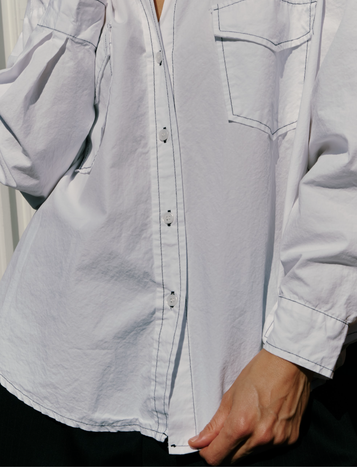 White oversized shirt with a person wearing it, focusing on the garment.