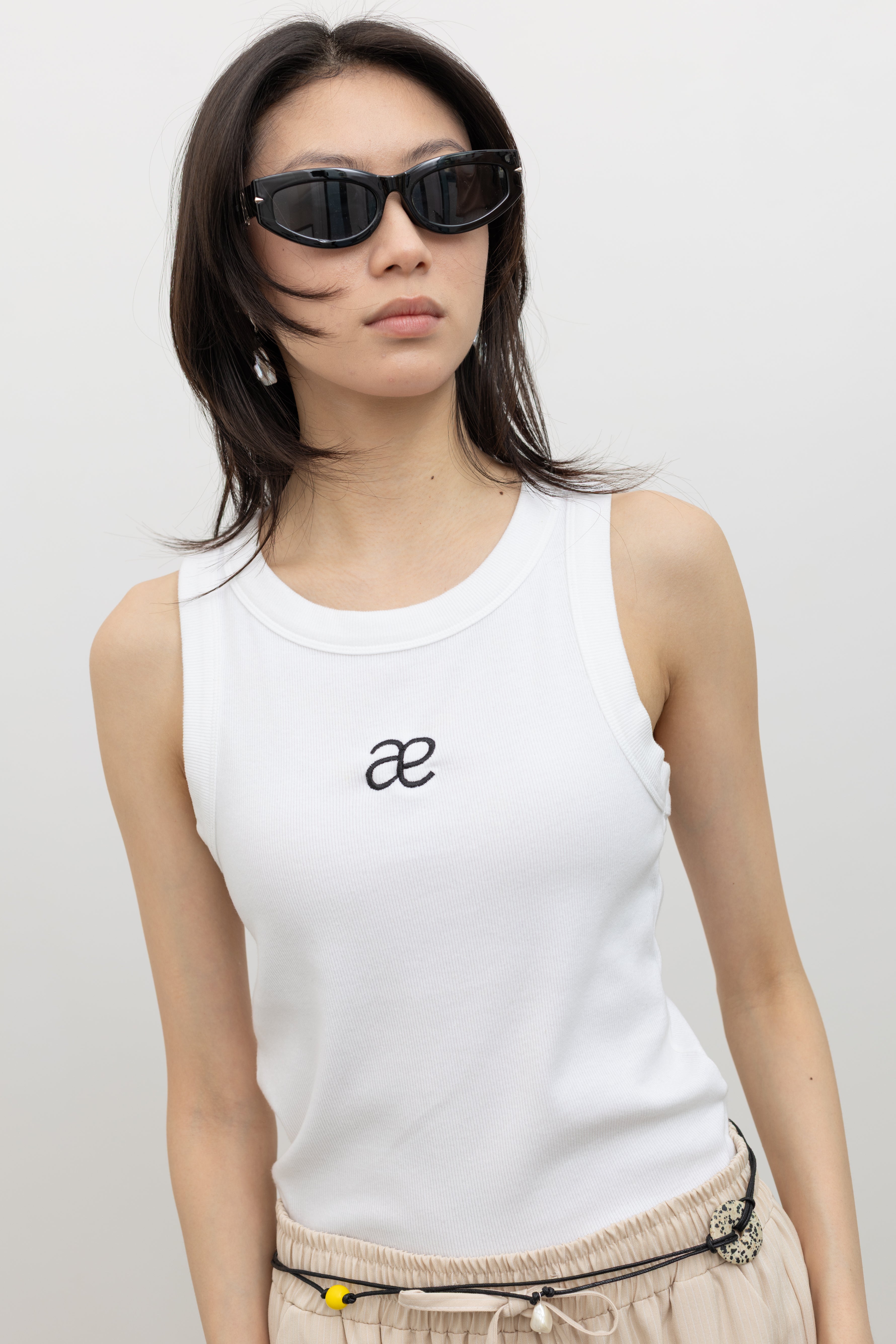 Alas Eius ribbed cotton blend tank top with embroidered logo detail, styled for modern women's minimalist wardrobe essentials at Alas Eius