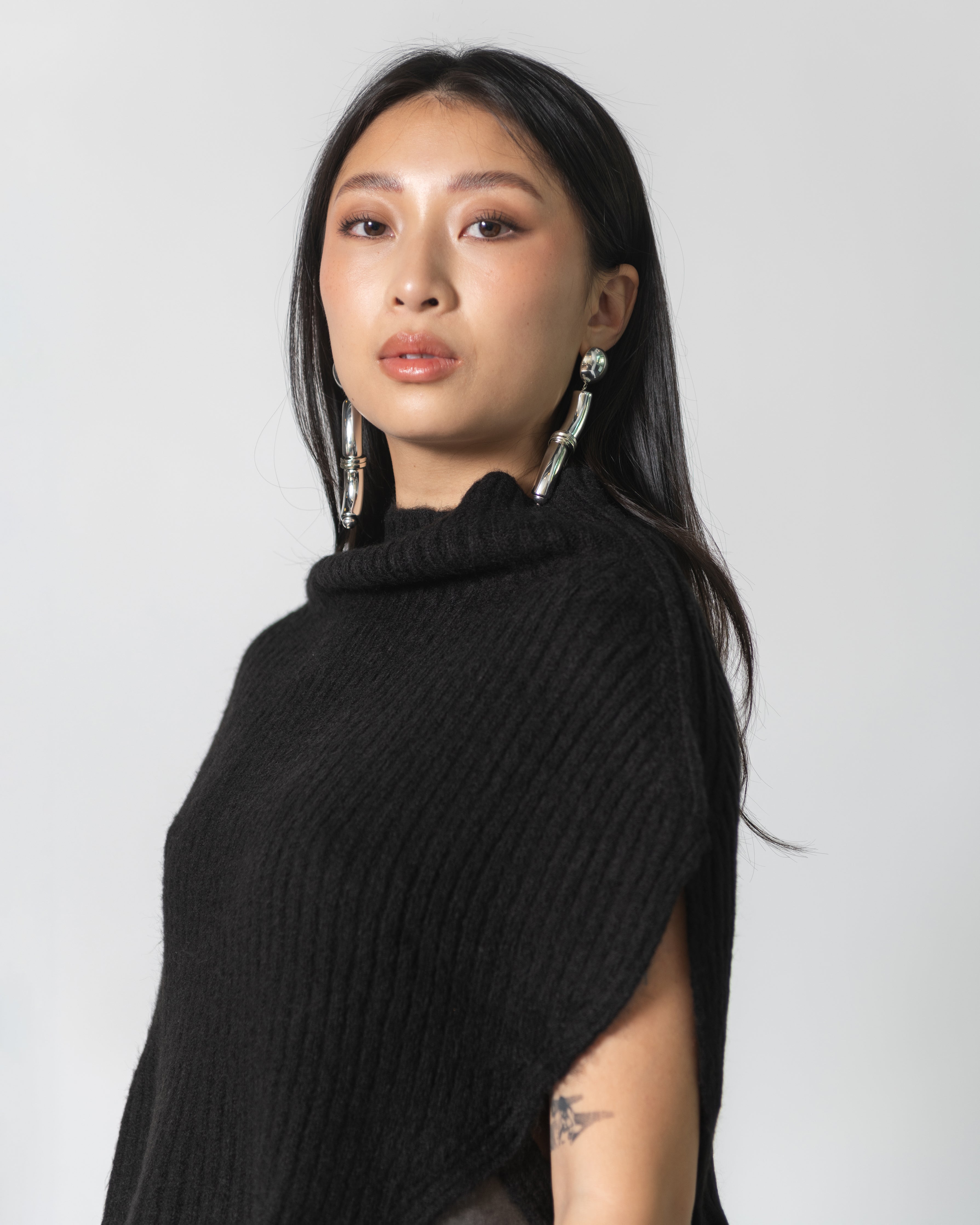 beautiful asian woman with statement earrings wearing a black ribbed neck warmer cape scarf at alas eius