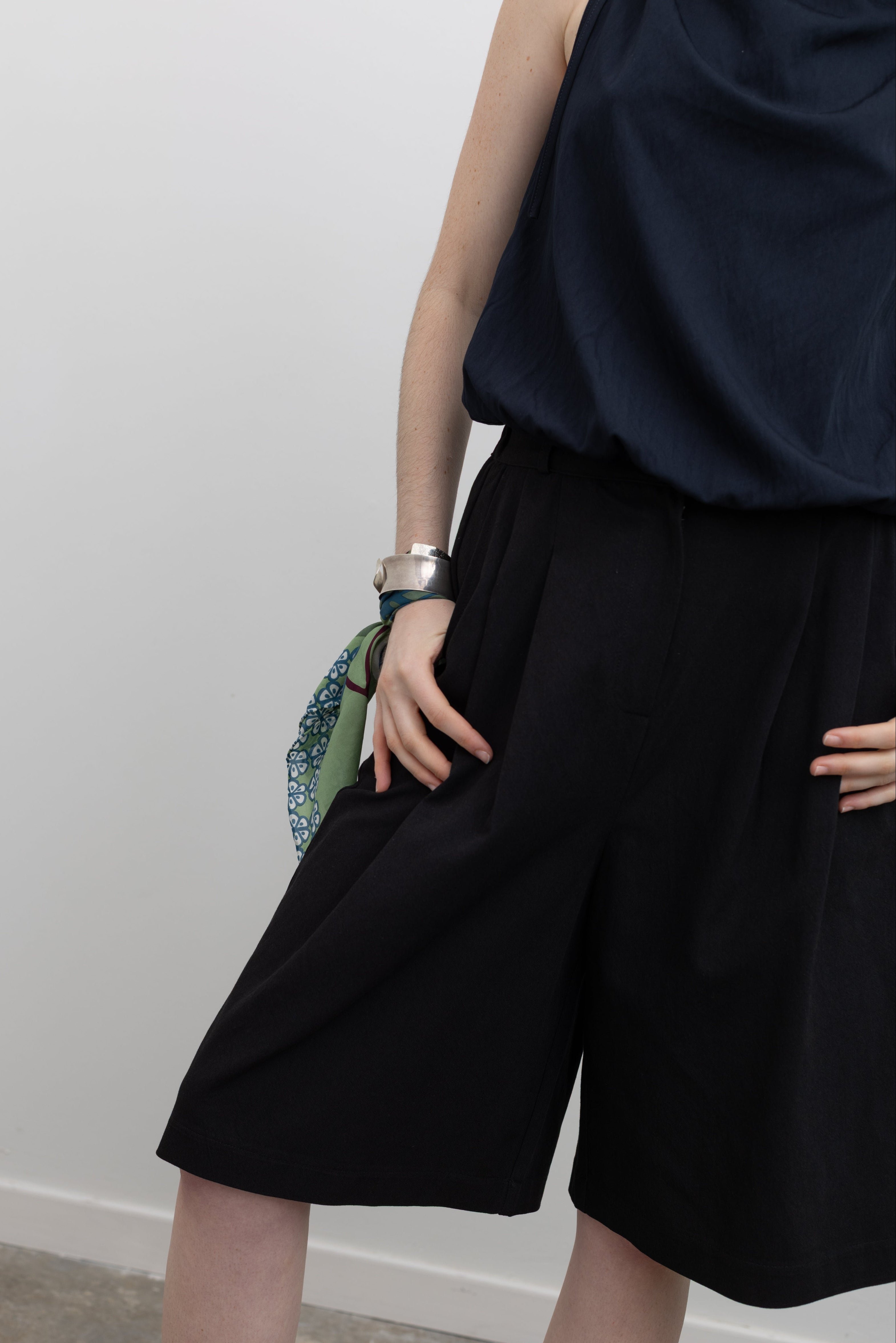 Collective black walking shorts with front pleats, side pockets, and a modern tailored fit at Alas Eius.