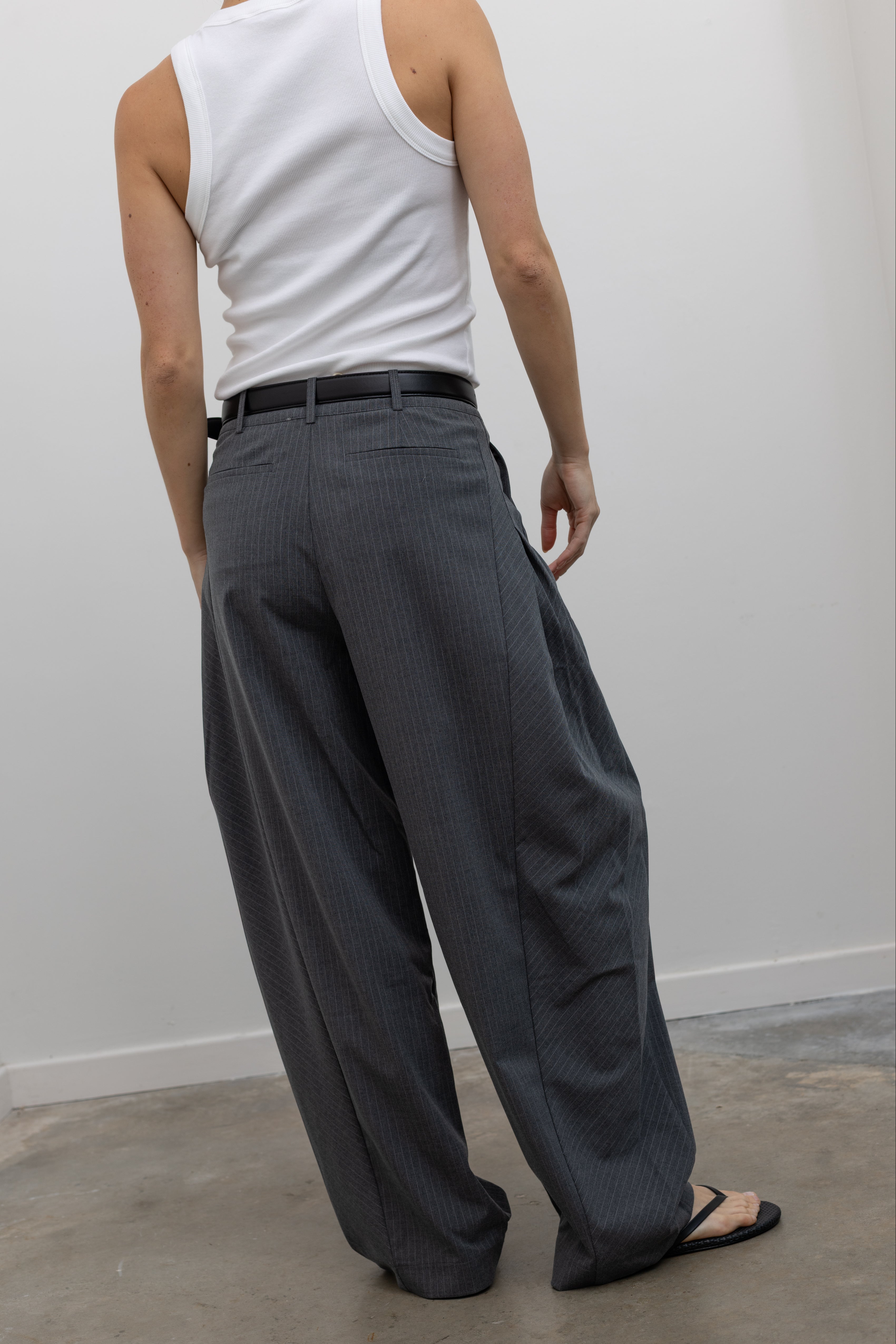 Collective charcoal pleated pinstripe pants with rounded barrel leg and fluid drape at Alas Eius