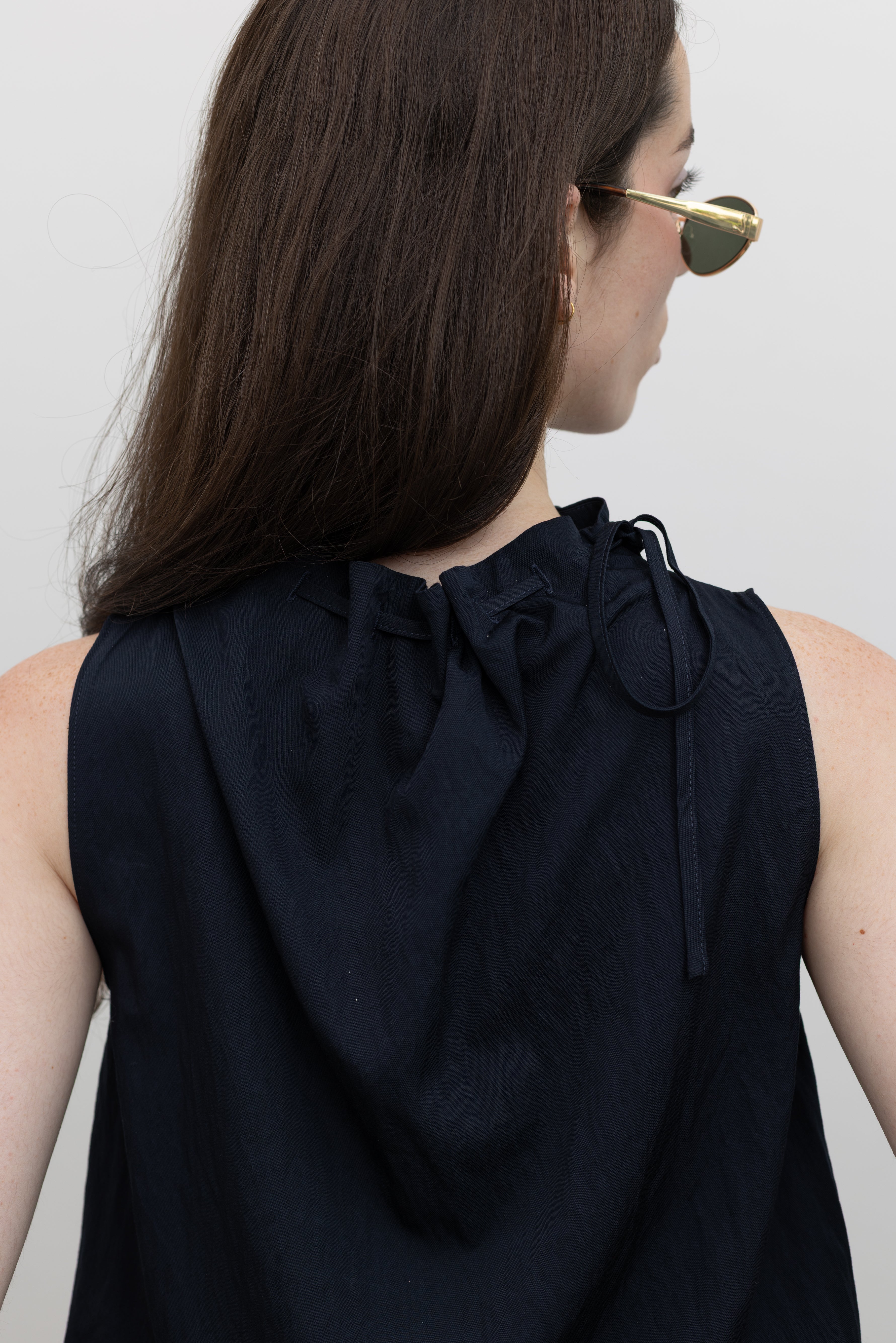 Collective sleeveless mock neck top featuring a self-tie detail and relaxed bubble hem for effortless chic outfits at Alas Eius.