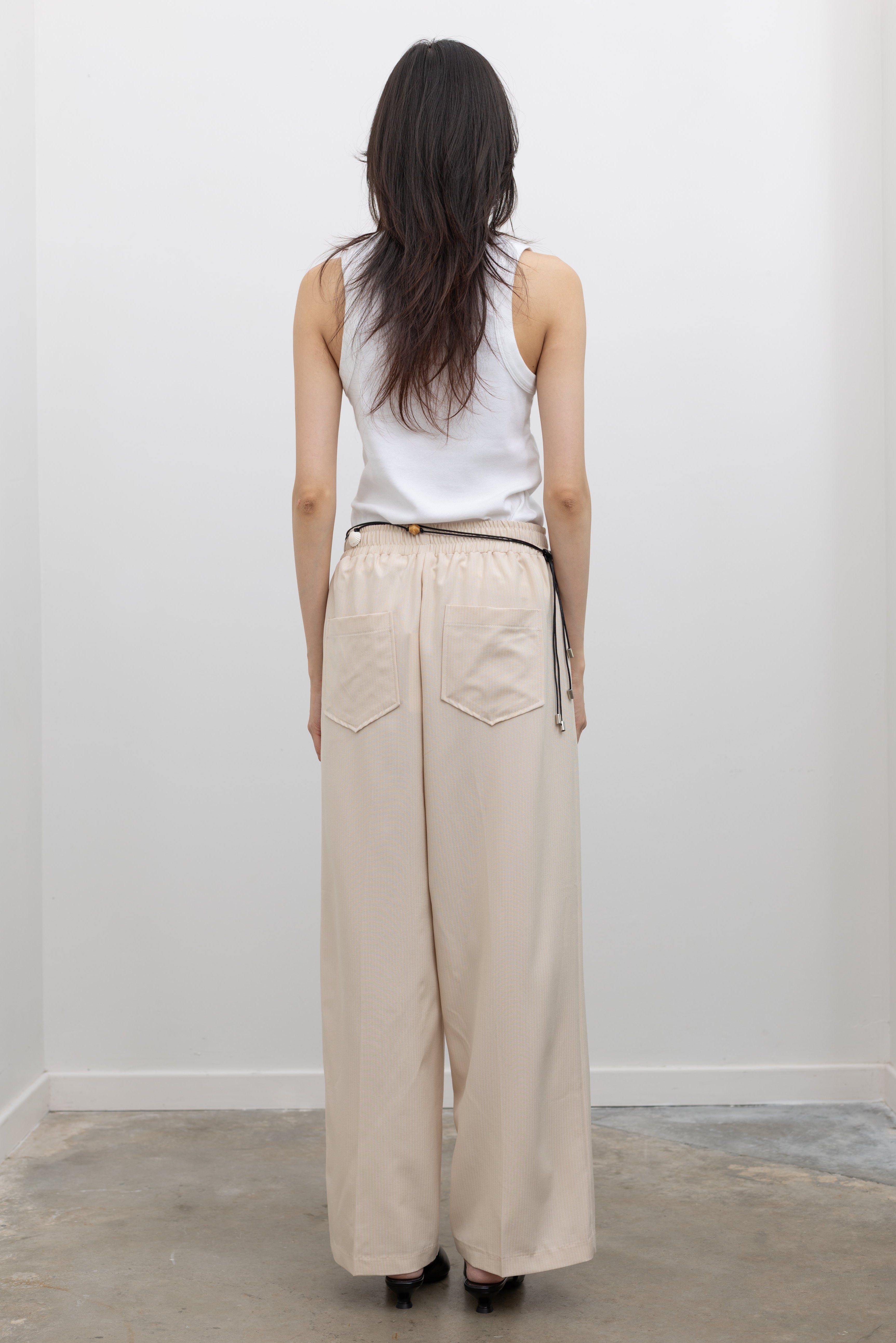 Collective wide-leg beige pinstripe pants with pleated front and side pockets, styled for contemporary women's workwear and off-duty fashion at Alas Eius