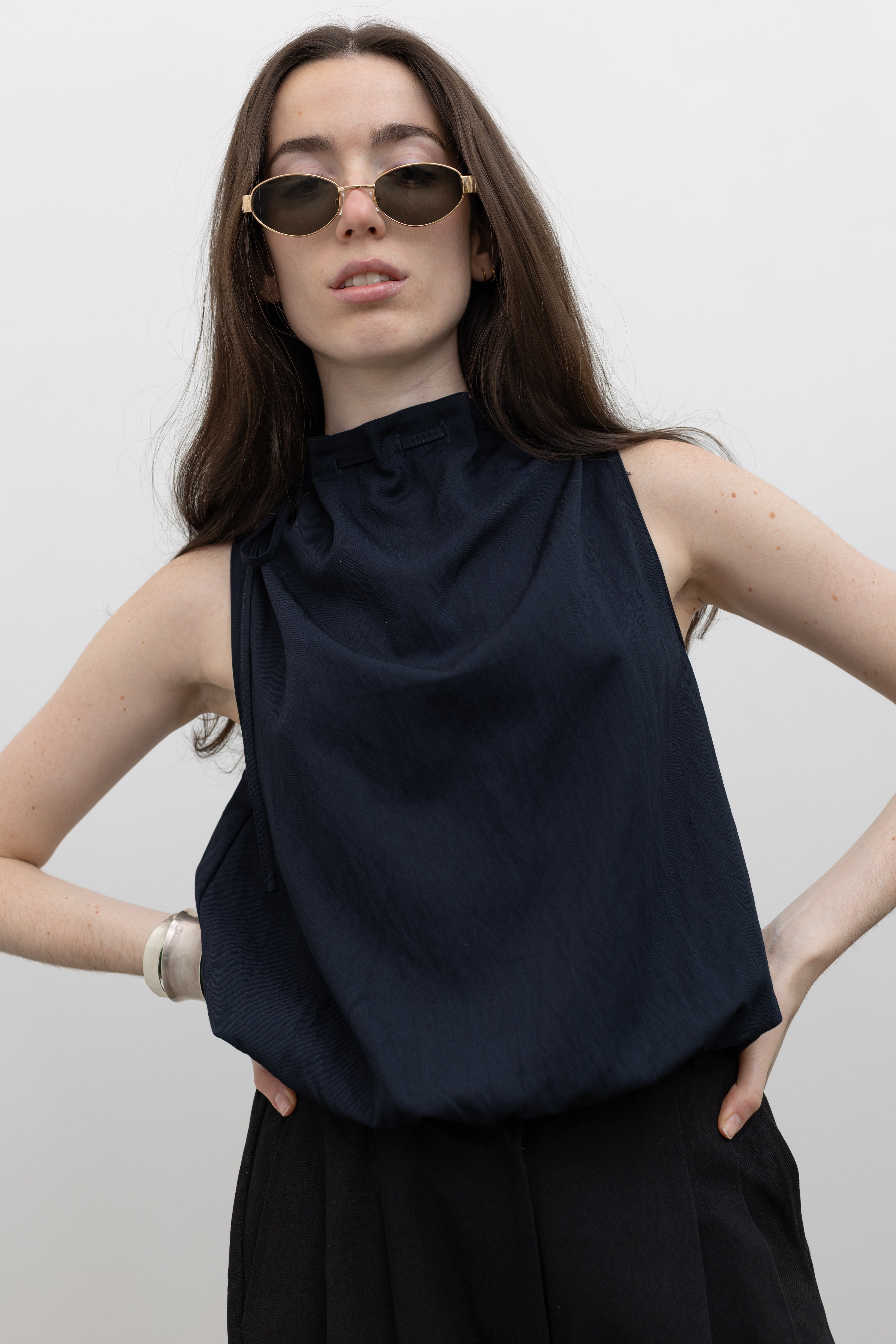 Collective women's sleeveless top with mock neck tie detail and bubble hem, styled as an elevated everyday blouse at Alas Eius.