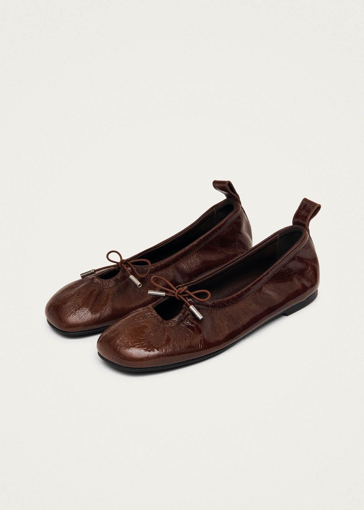 Alohas brown patent leather ballet flats with unlined upper and drawstring detail, shown in side profile at Alas Eius