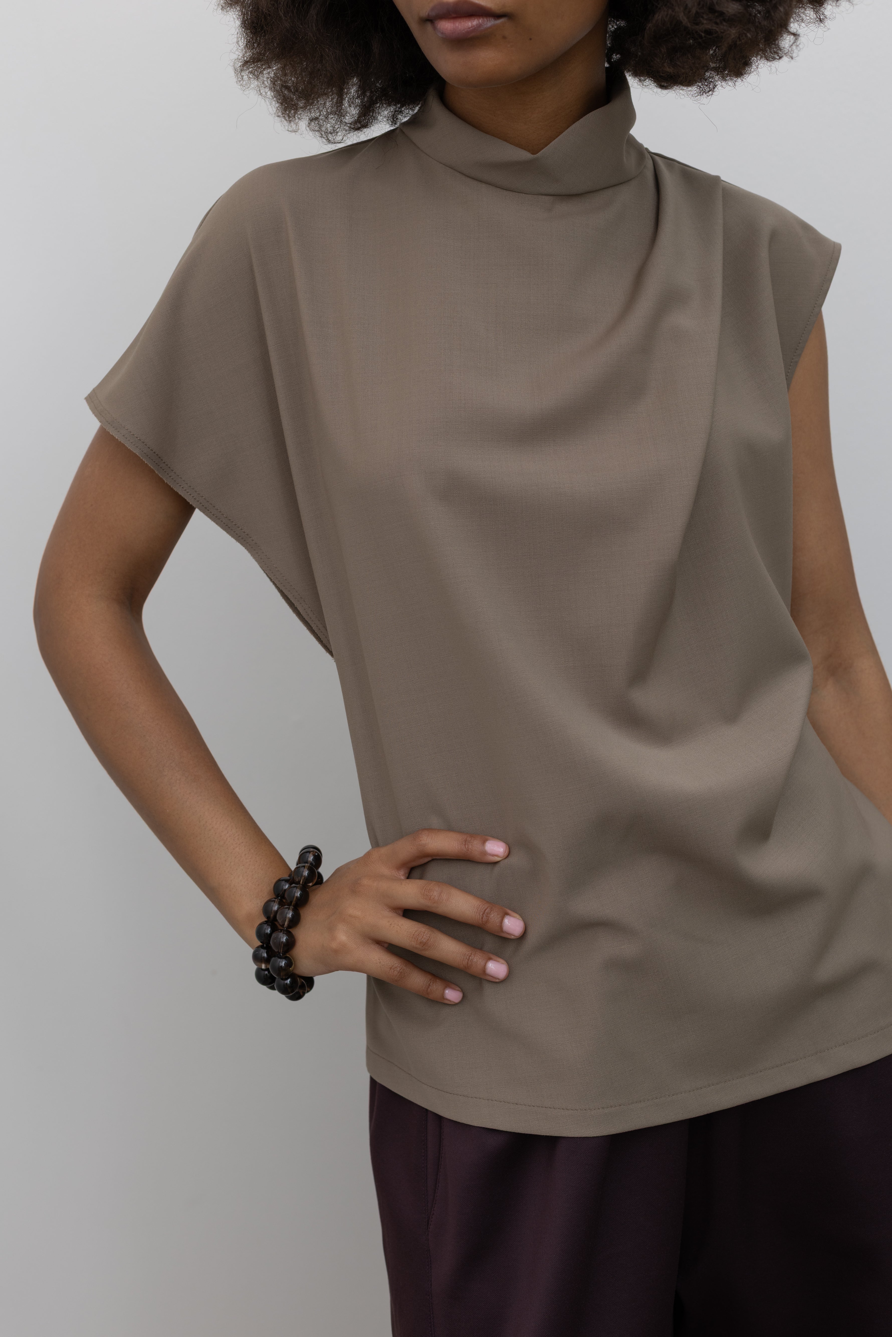 Tela draped wool-blend top featuring an asymmetrical silhouette and back neck button closure at alas eius.