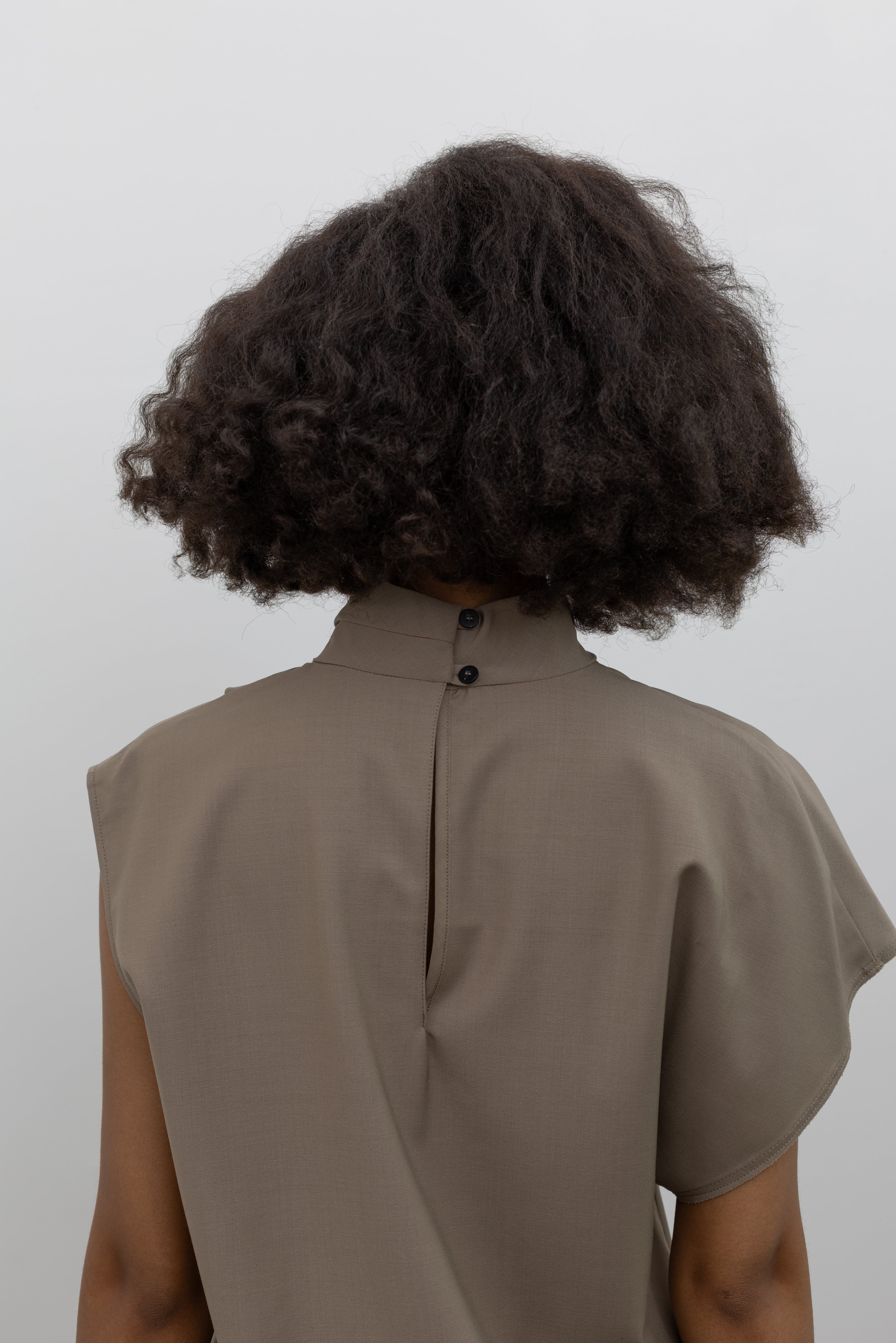 Tela elevated wool-blend top with a fluid draped front, high neckline, and modern asymmetrical sleeves at alas eius.