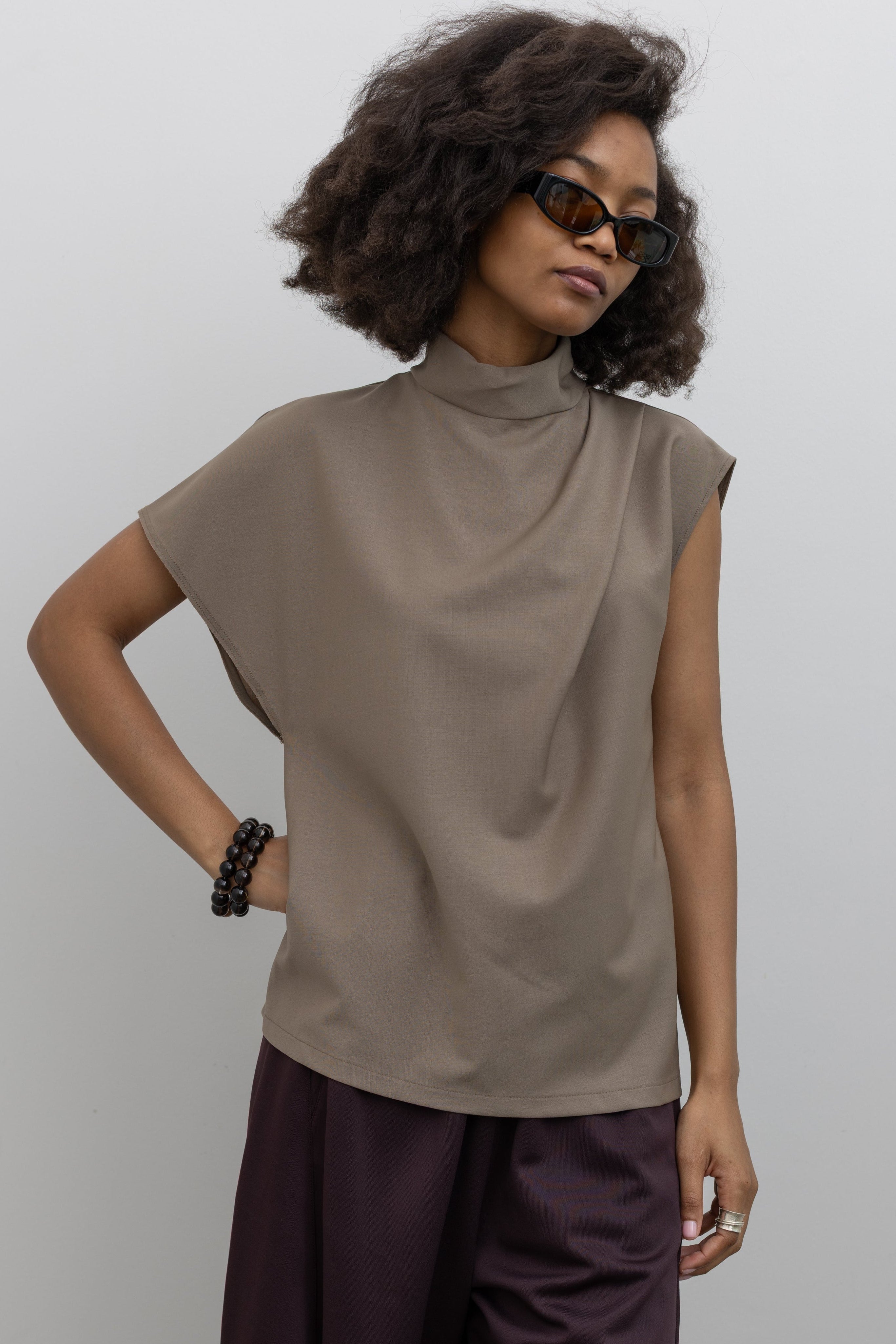Tela wool-blend top featuring asymmetrical sleeves, a draped front, and a refined high neckline with back button closure at alas eius.
