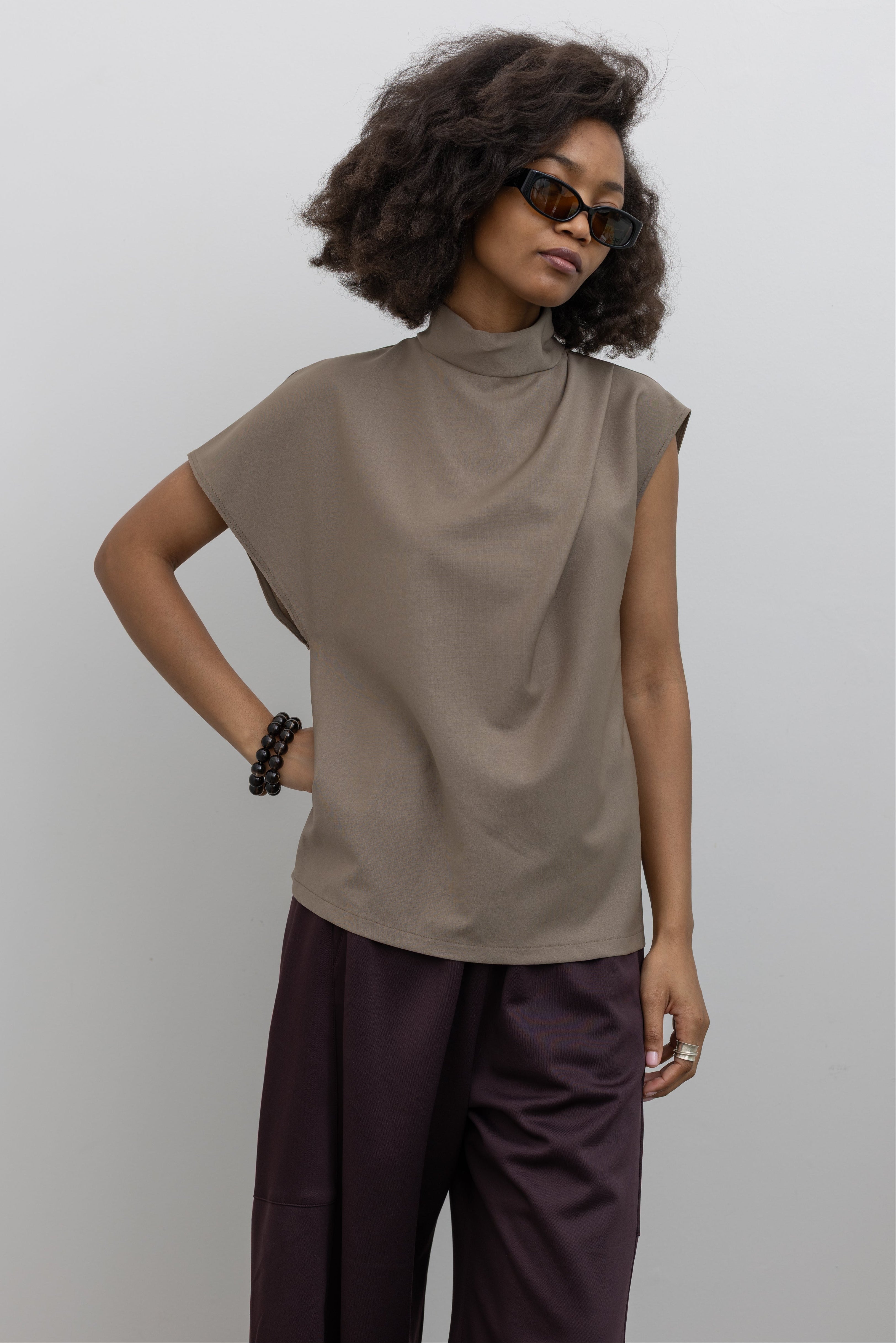 Tela wool-blend top featuring asymmetrical sleeves, a draped front, and a refined high neckline with back button closure at alas eius.