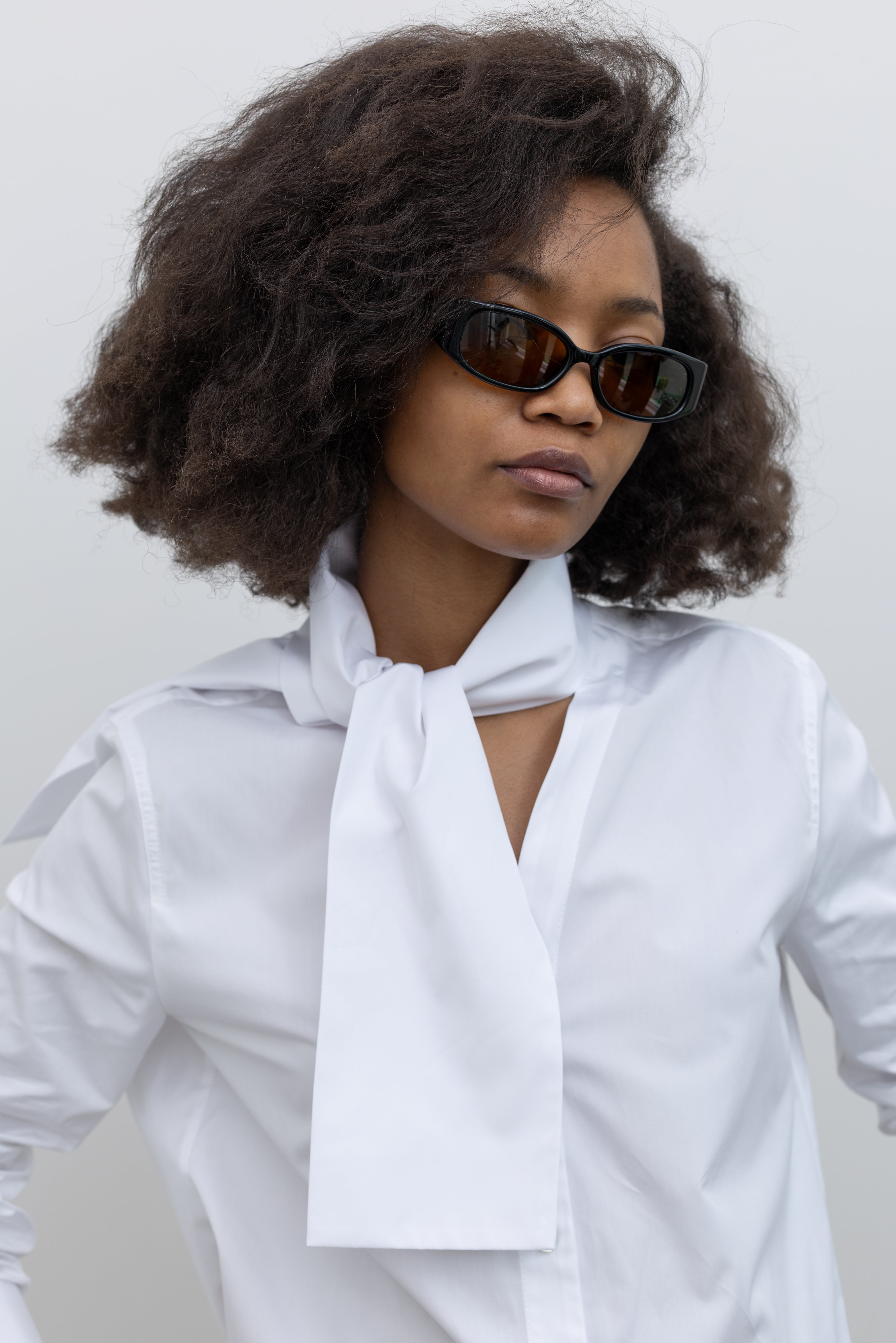Tela Deanna white button-down with relaxed structure, wide cuffs, and chic ascot-inspired detailing at alas eius.